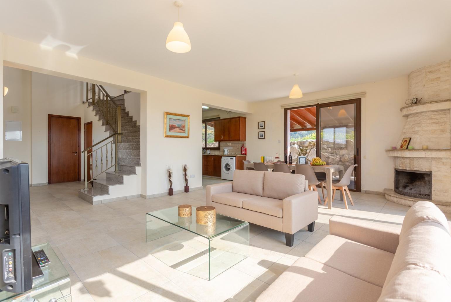 Open-plan living room with sofas, dining area, kitchen, ornamental fireplace, A/C, WiFi internet, satellite TV, DVD player, and pool terrace access