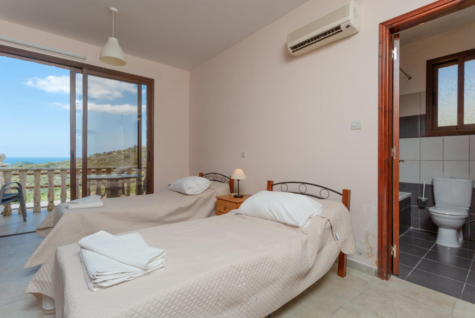 Twin bedroom with en suite bathroom, A/C, and terrace access with panoramic views of the sea and countryside