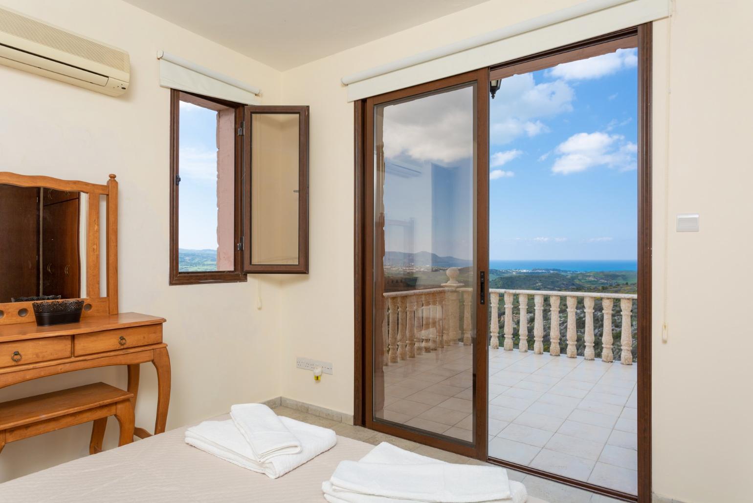 Double bedroom with en suite bathroom, A/C, and balcony access with panoramic views of the sea and countryside