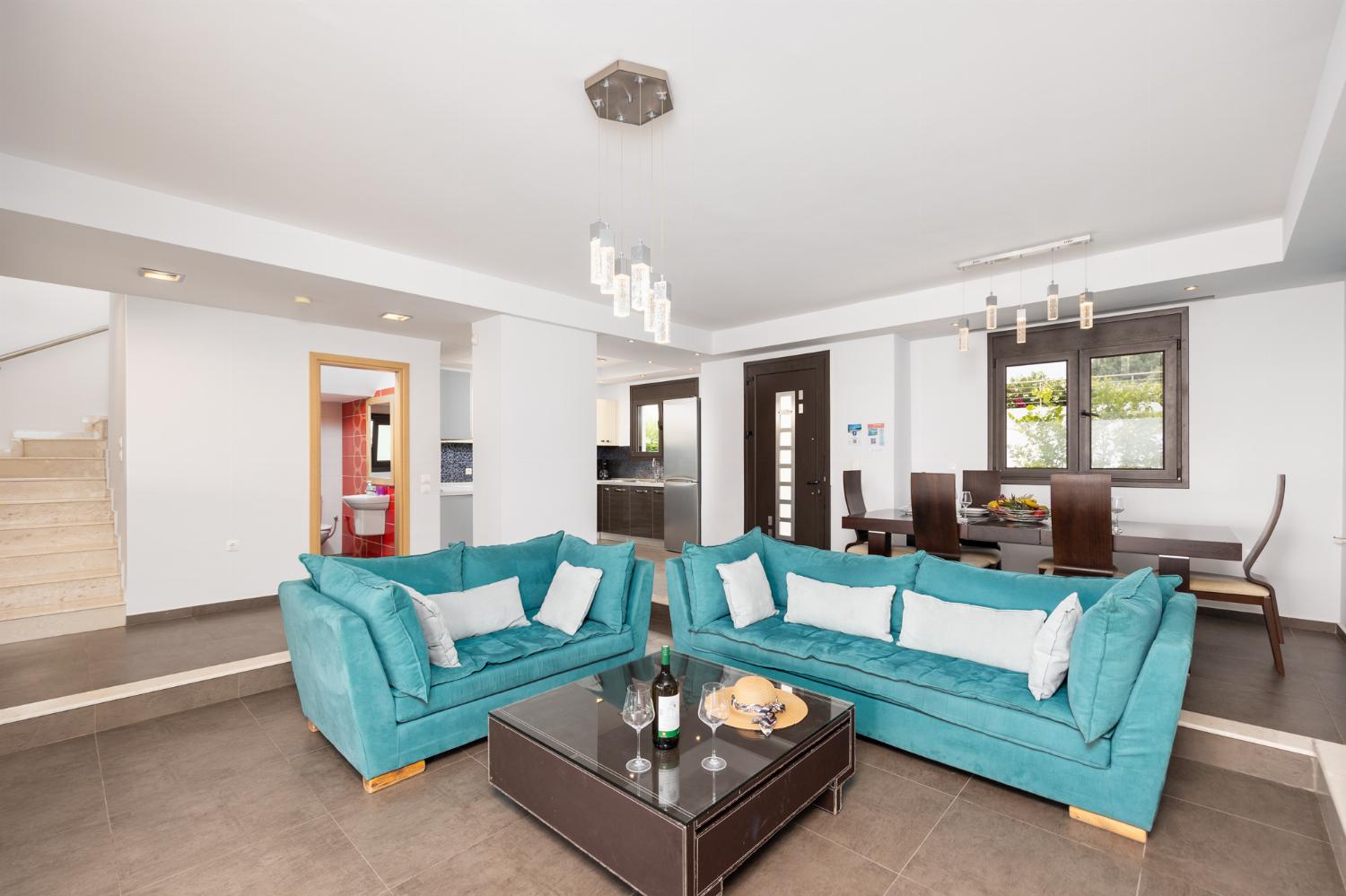 Open-plan living room with sofas, dining area, kitchen, ornamental fireplace, A/C, WiFi internet, satellite TV, and sea views