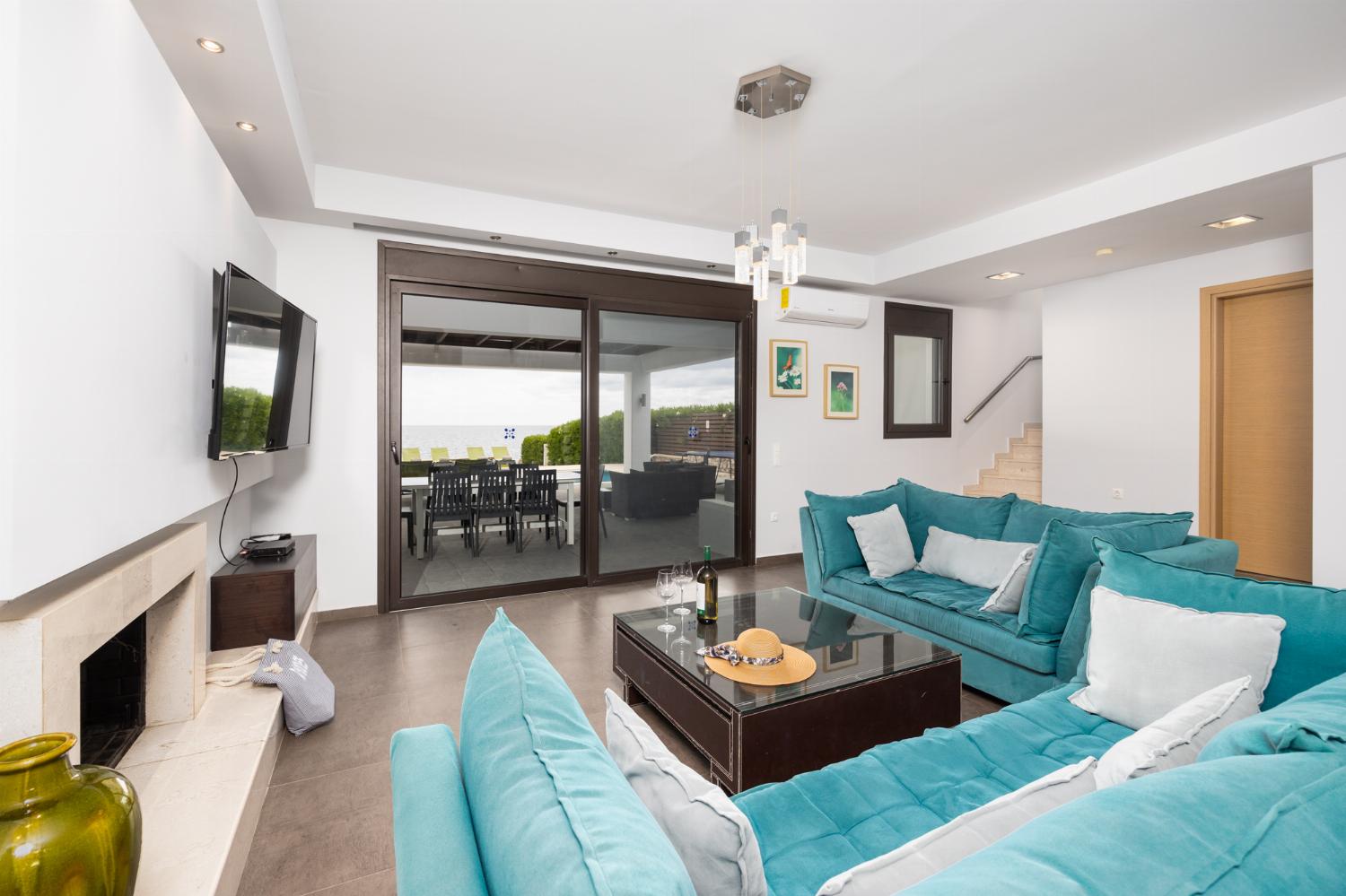 Open-plan living room with sofas, dining area, kitchen, ornamental fireplace, A/C, WiFi internet, satellite TV, and sea views