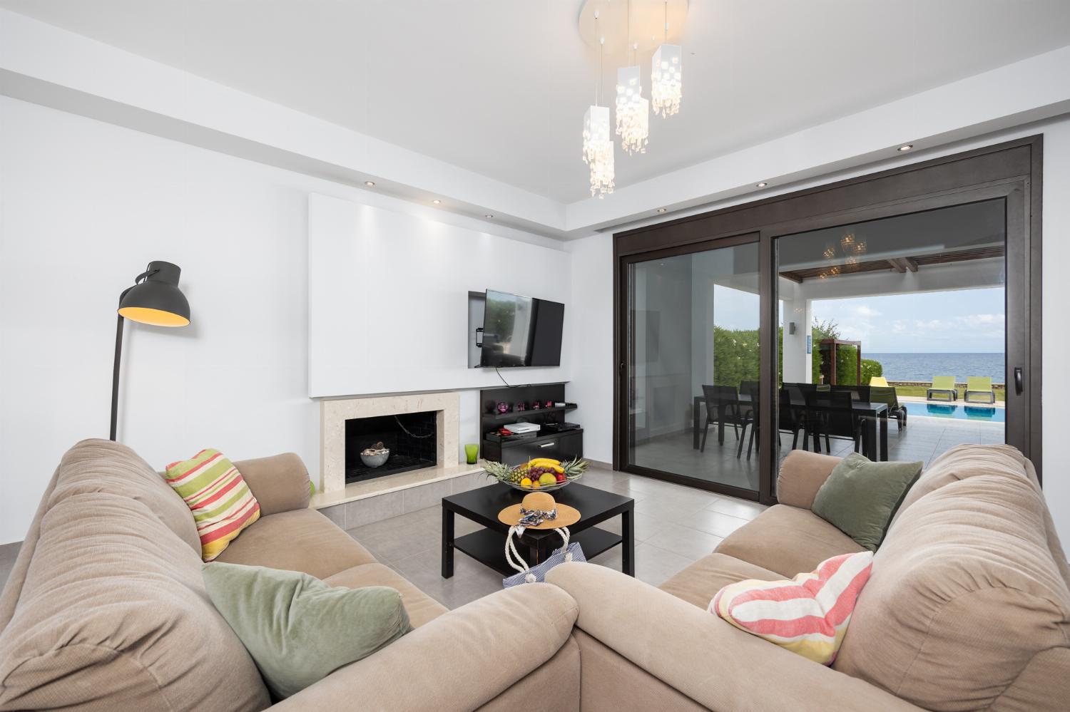 Open-plan living room with sofas, dining area, kitchen, ornamental fireplace, A/C, WiFi internet, satellite TV, and sea views