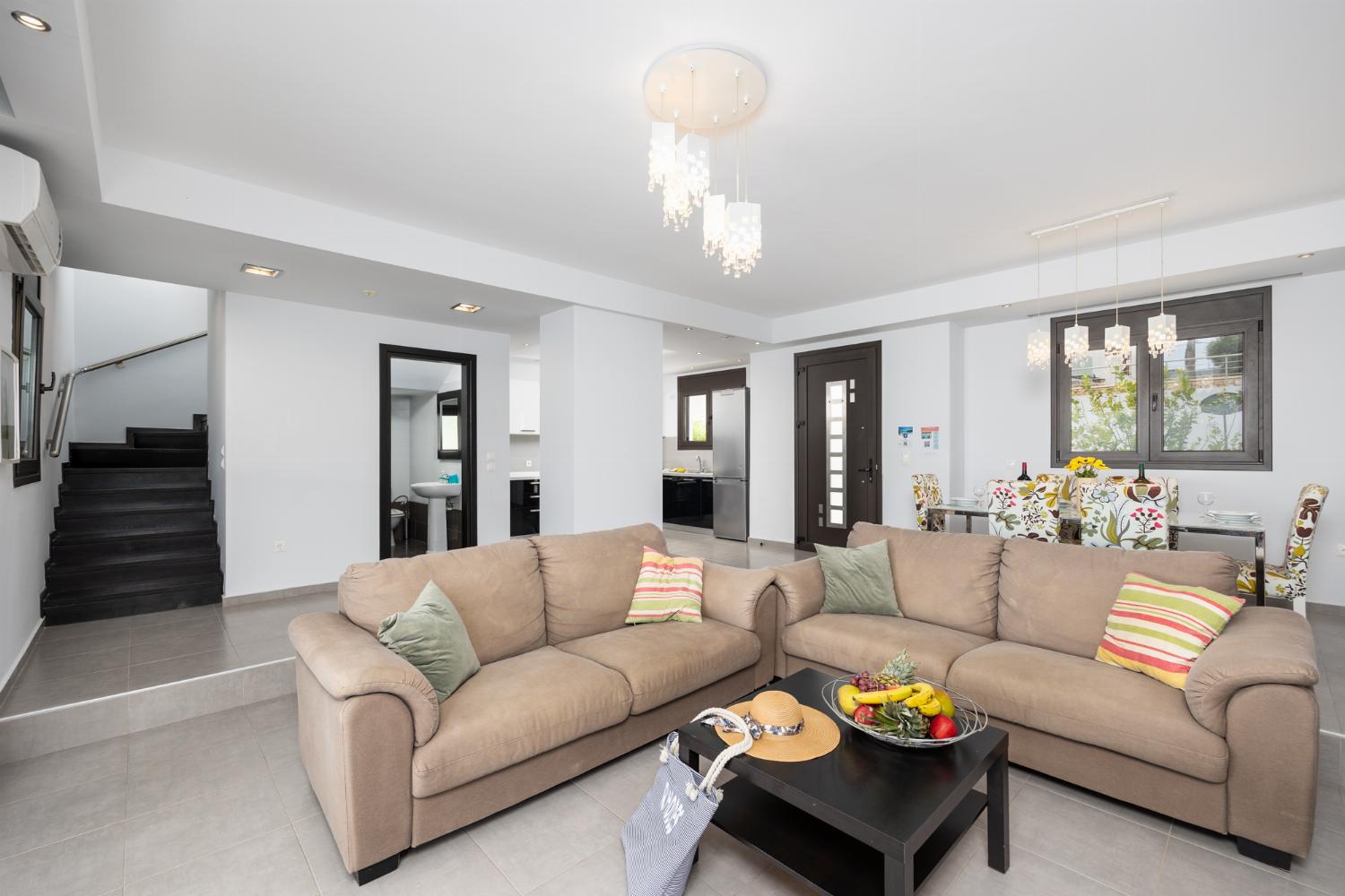 Open-plan living room with sofas, dining area, kitchen, ornamental fireplace, A/C, WiFi internet, satellite TV, and sea views