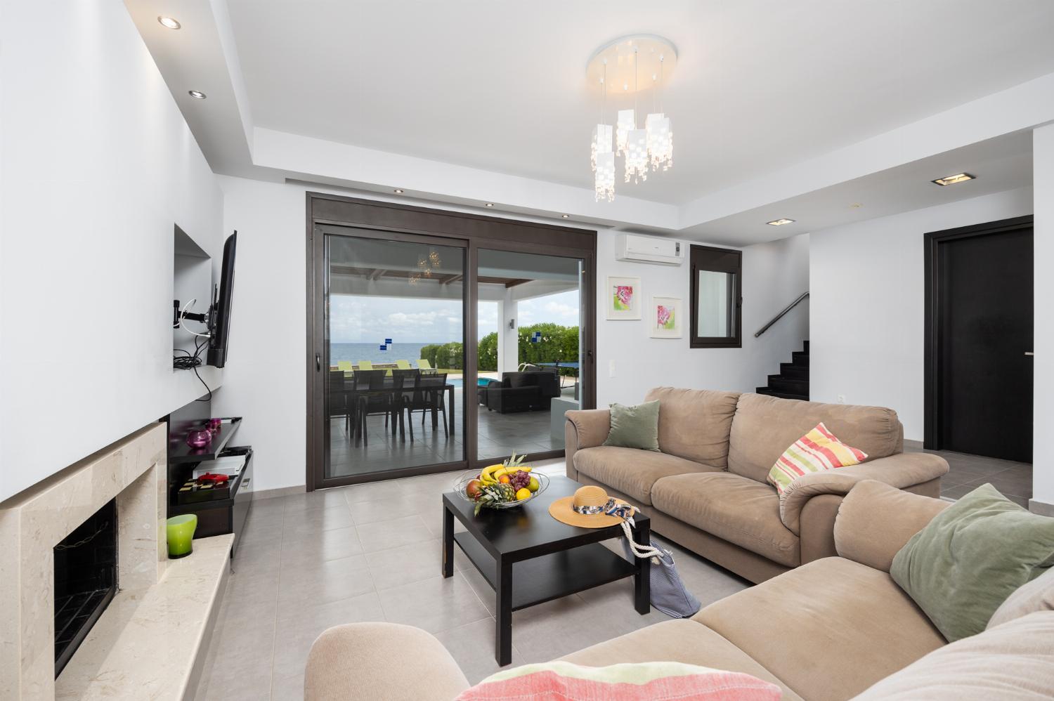 Open-plan living room with sofas, dining area, kitchen, ornamental fireplace, A/C, WiFi internet, satellite TV, and sea views