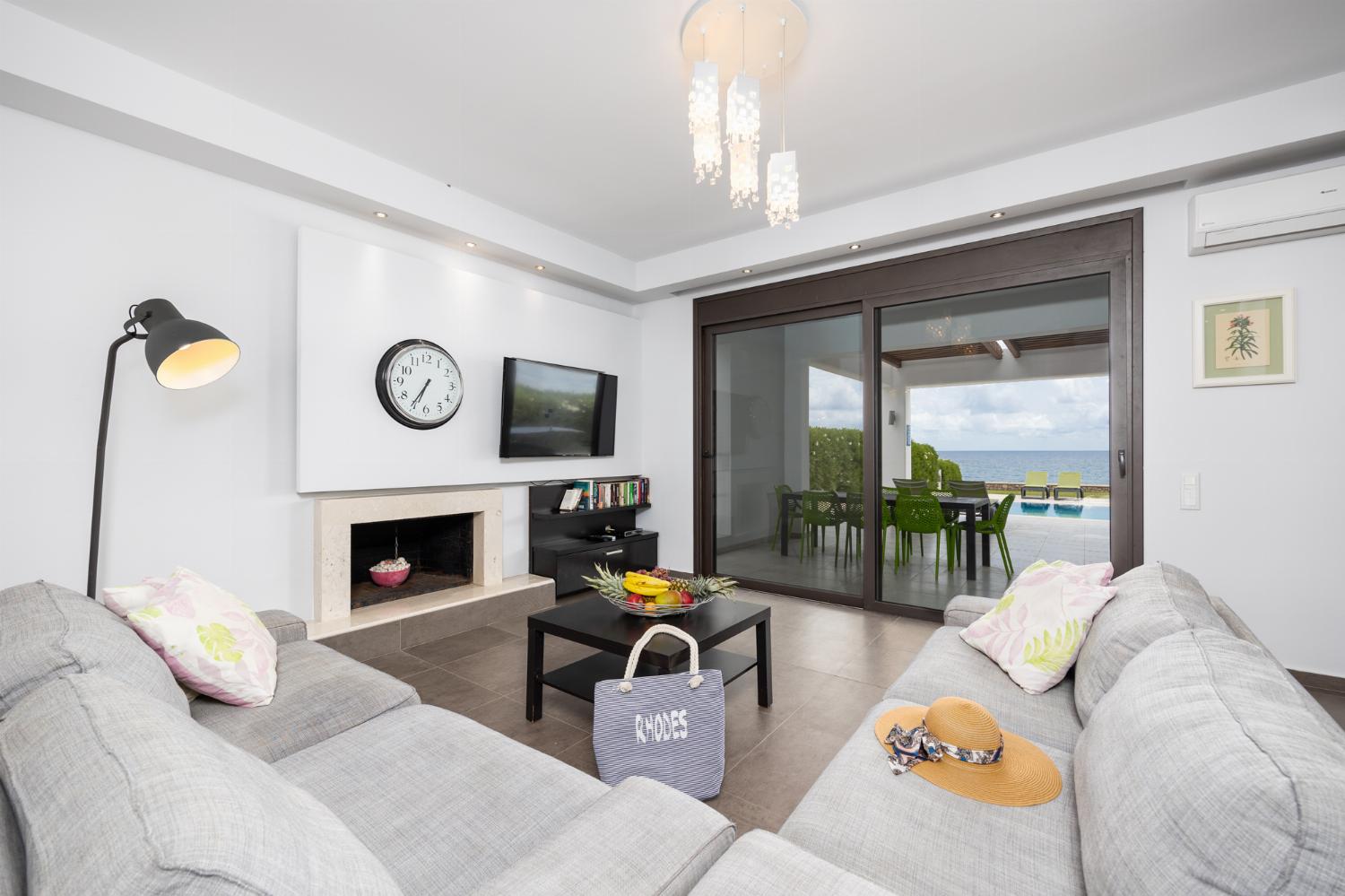 Open-plan living room with sofas, dining area, kitchen, ornamental fireplace, A/C, WiFi internet, satellite TV, and sea views