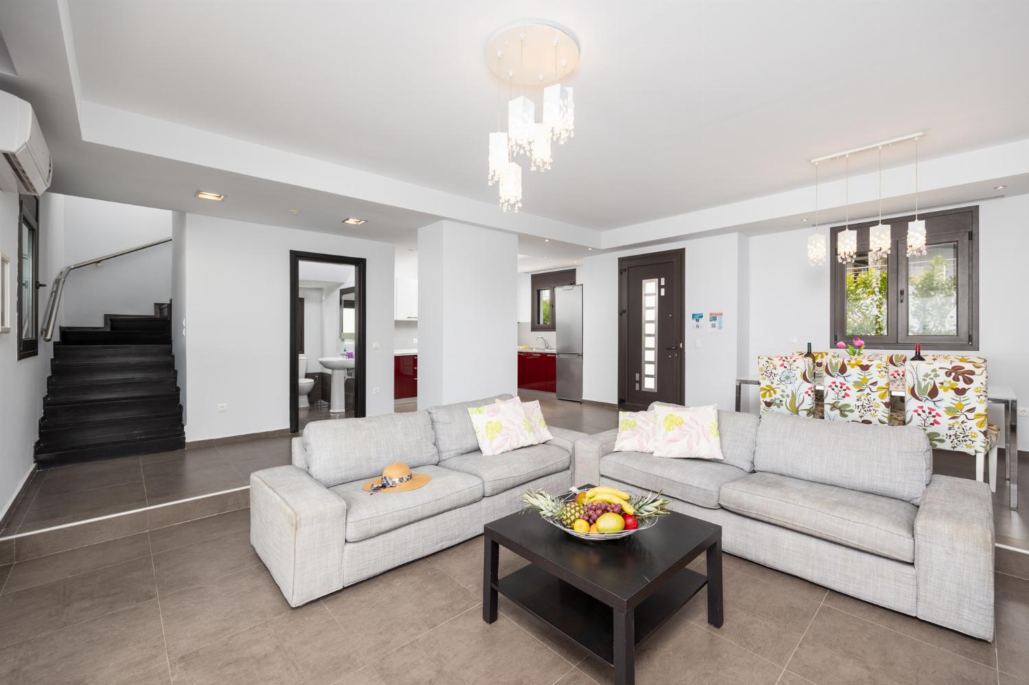 Open-plan living room with sofas, dining area, kitchen, ornamental fireplace, A/C, WiFi internet, satellite TV, and sea views