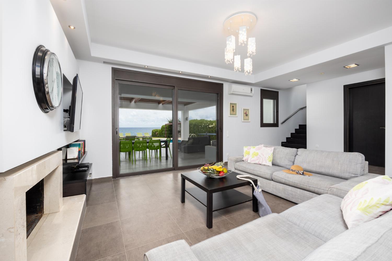 Open-plan living room with sofas, dining area, kitchen, ornamental fireplace, A/C, WiFi internet, satellite TV, and sea views