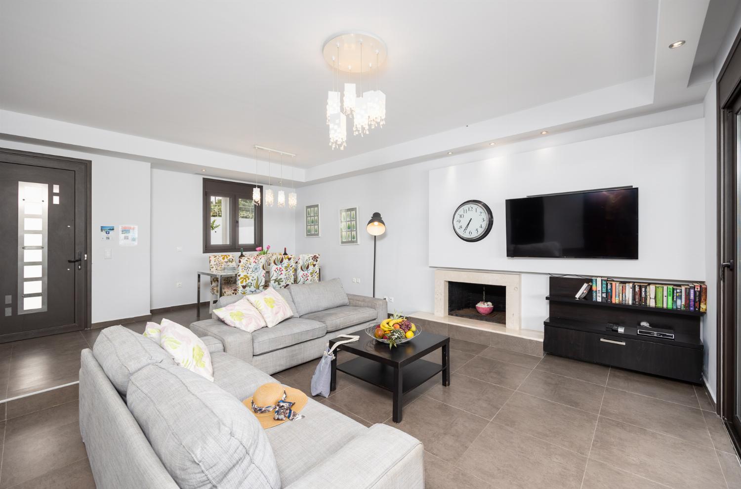 Open-plan living room with sofas, dining area, kitchen, ornamental fireplace, A/C, WiFi internet, satellite TV, and sea views