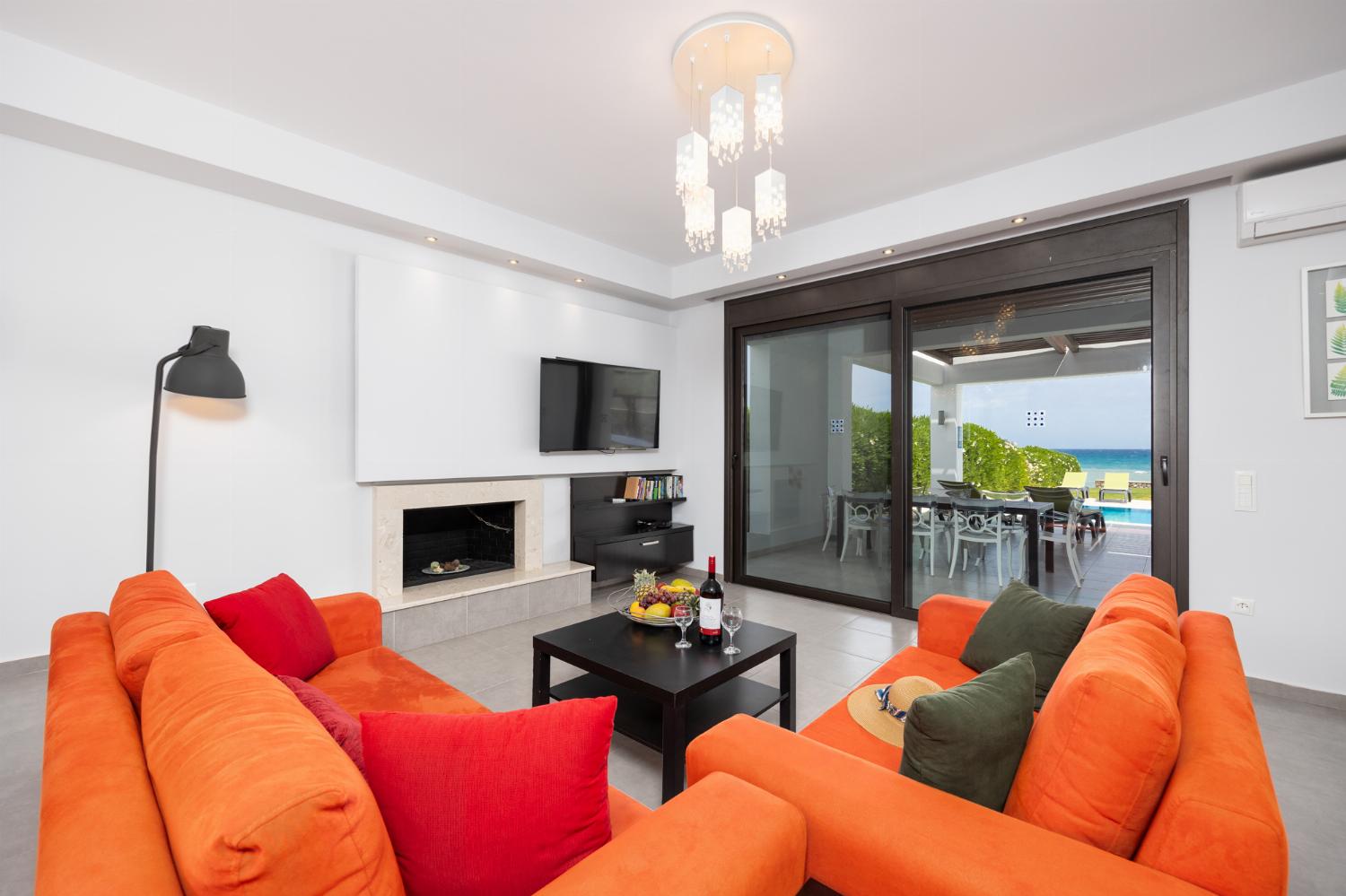 Open-plan living room with sofas, dining area, kitchen, ornamental fireplace, A/C, WiFi internet, satellite TV, and sea views