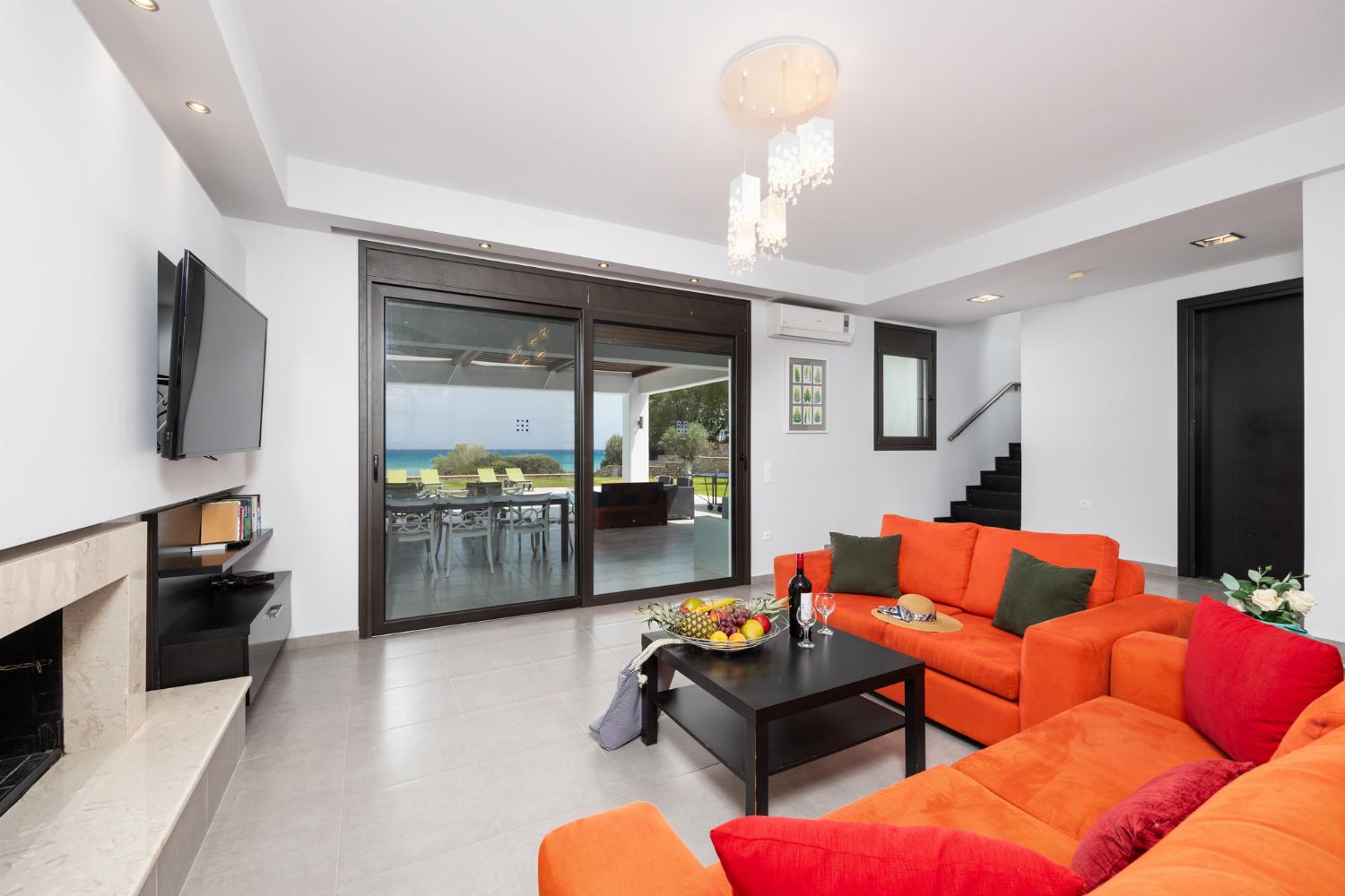 Open-plan living room with sofas, dining area, kitchen, ornamental fireplace, A/C, WiFi internet, satellite TV, and sea views