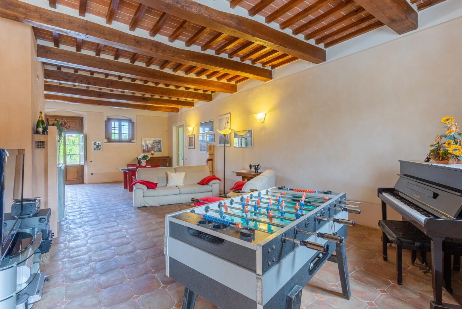 Living room with sofas, dining area, ornamental fireplace, piano, foosball table, WiFi internet, satellite TV, DVD player, and terrace access