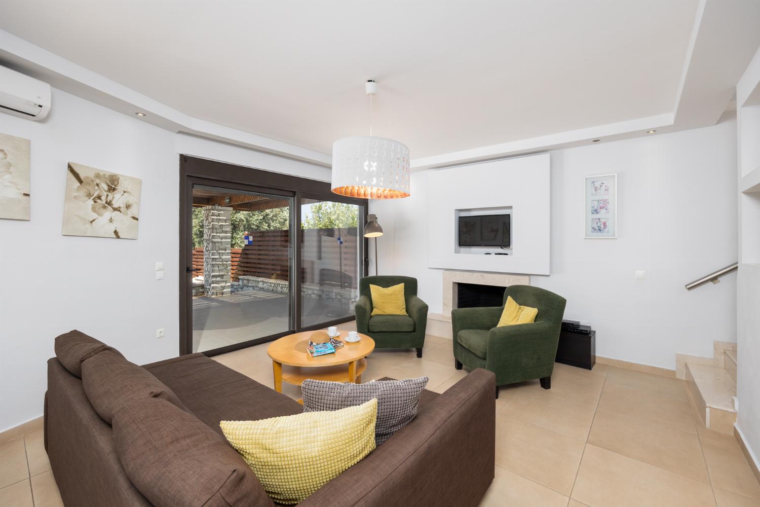Open-plan living room with sofa, dining area, kitchen, ornamental fireplace, A/C, WiFi internet, and satellite TV