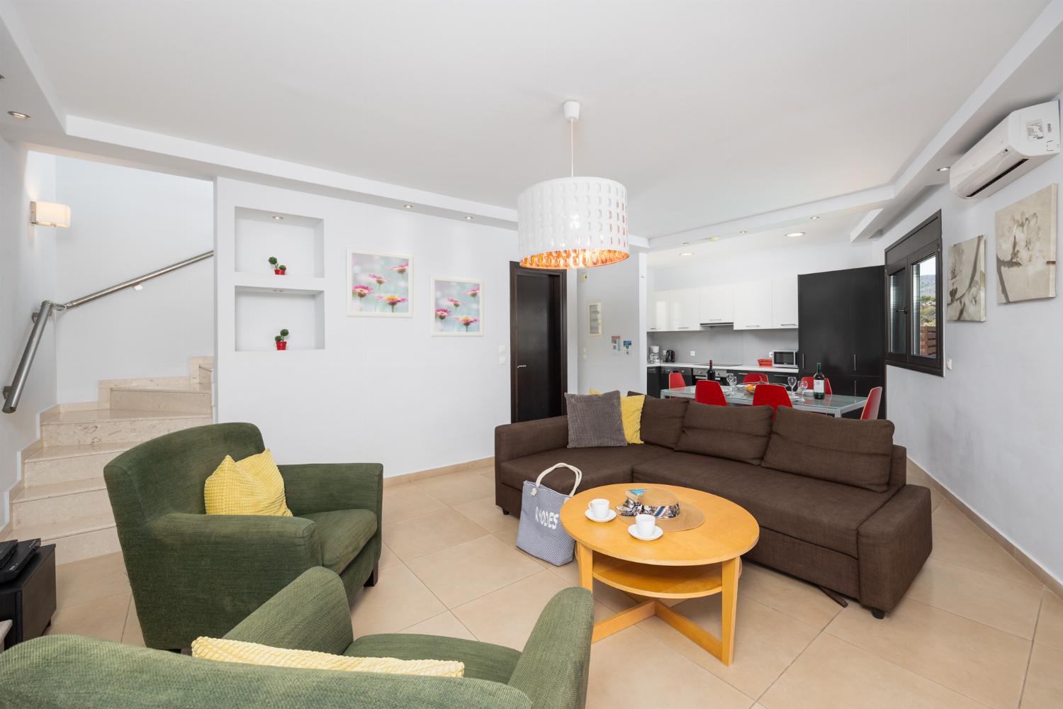 Open-plan living room with sofa, dining area, kitchen, ornamental fireplace, A/C, WiFi internet, and satellite TV