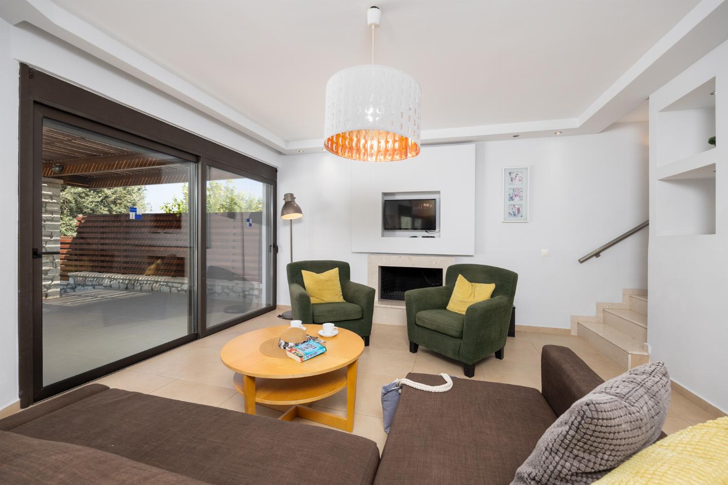 Open-plan living room with sofa, dining area, kitchen, ornamental fireplace, A/C, WiFi internet, and satellite TV