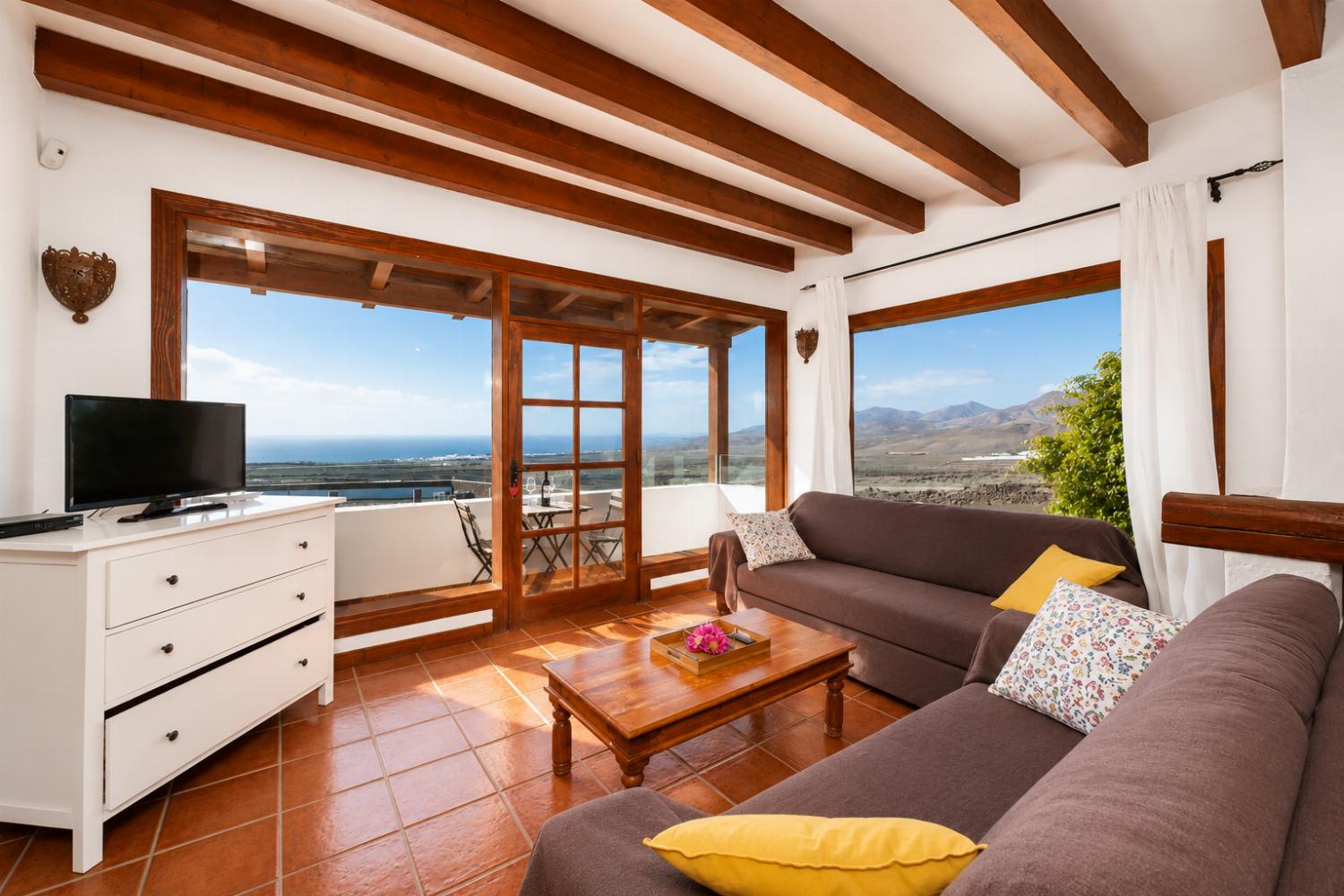 Open-plan living room on first floor with sofas, dining area, kitchen, ornamental fireplace, WiFi internet, satellite TV, and sea views