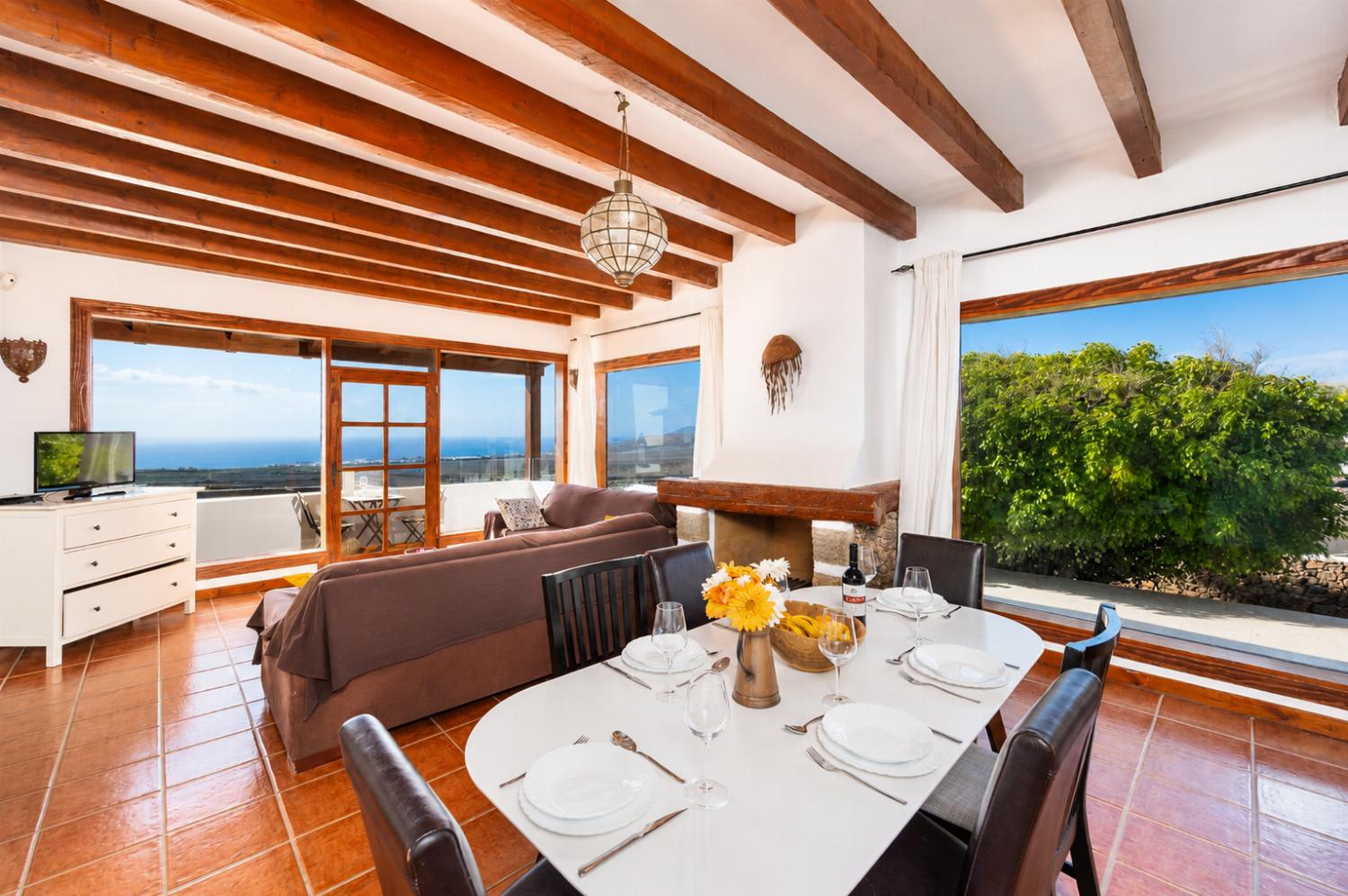Open-plan living room on first floor with sofas, dining area, kitchen, ornamental fireplace, WiFi internet, satellite TV, and sea views