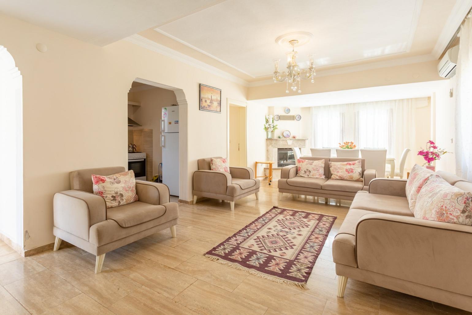 Open-plan living room with sofas, dining area, kitchen, ornamental fireplace, A/C, WiFi internet, satellite TV, and DVD player