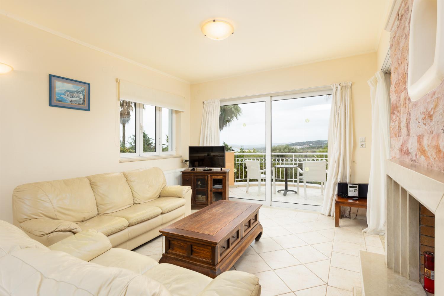 Open-plan living room with sofas, dining area, kitchen, ornamental fireplace, A/C, WiFi internet, and satellite TV