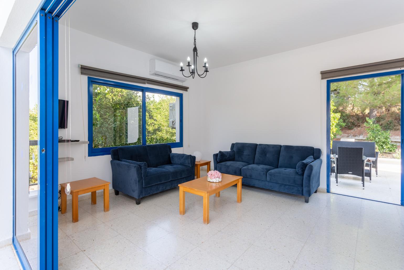 Open-plan living room with sofas, dining area, kitchen, A/C, WiFi internet, satellite TV, DVD player, and terrace access