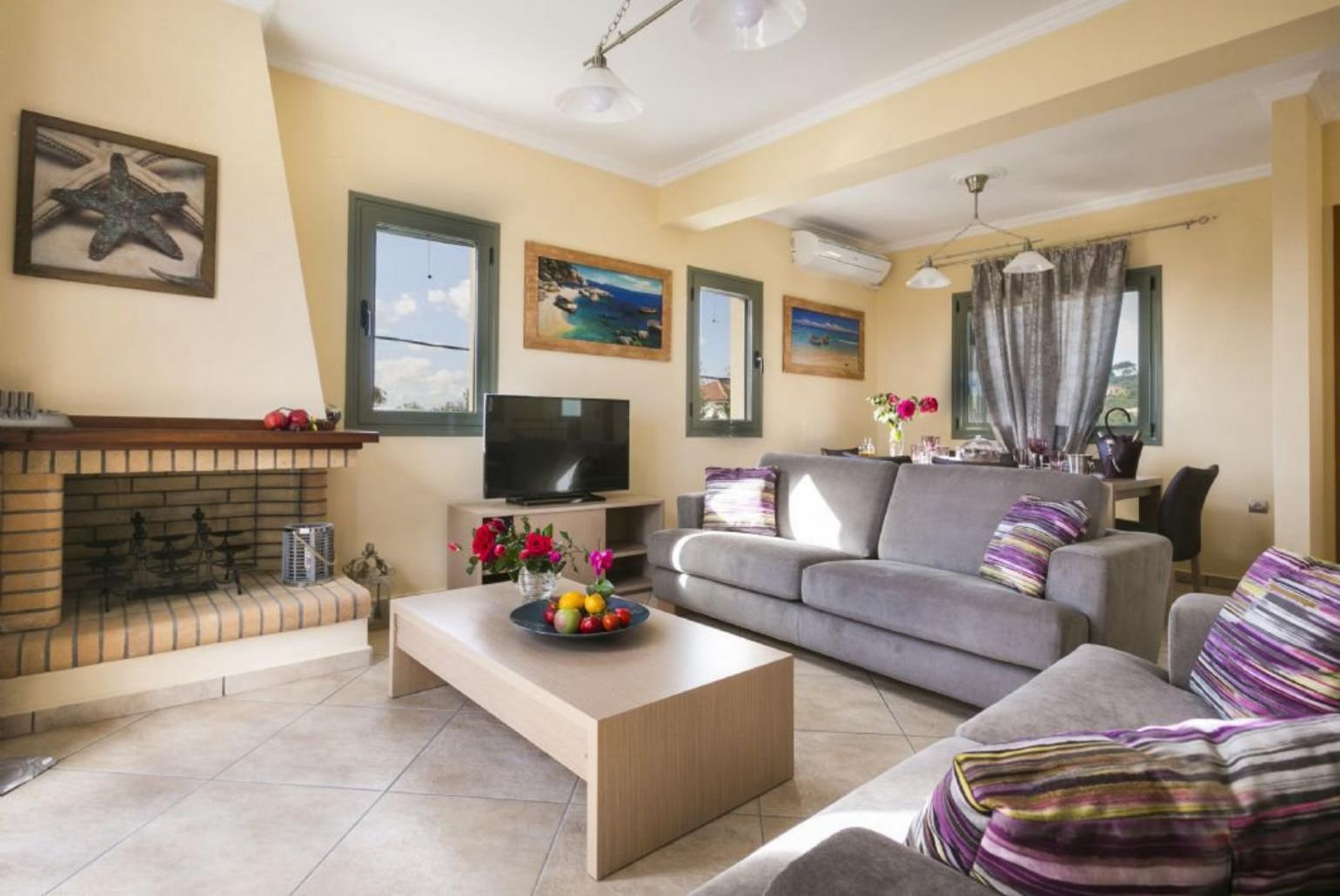 Open-plan living room with sofas, dining area, kitchen, ornamental fireplace, A/C, WiFi internet, satellite TV, DVD player, and sea views