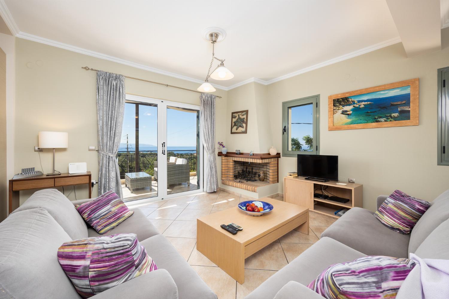Open-plan living room with sofas, dining areas, kitchen, ornamental fireplace, A/C, WiFi internet, satellite TV, and sea views