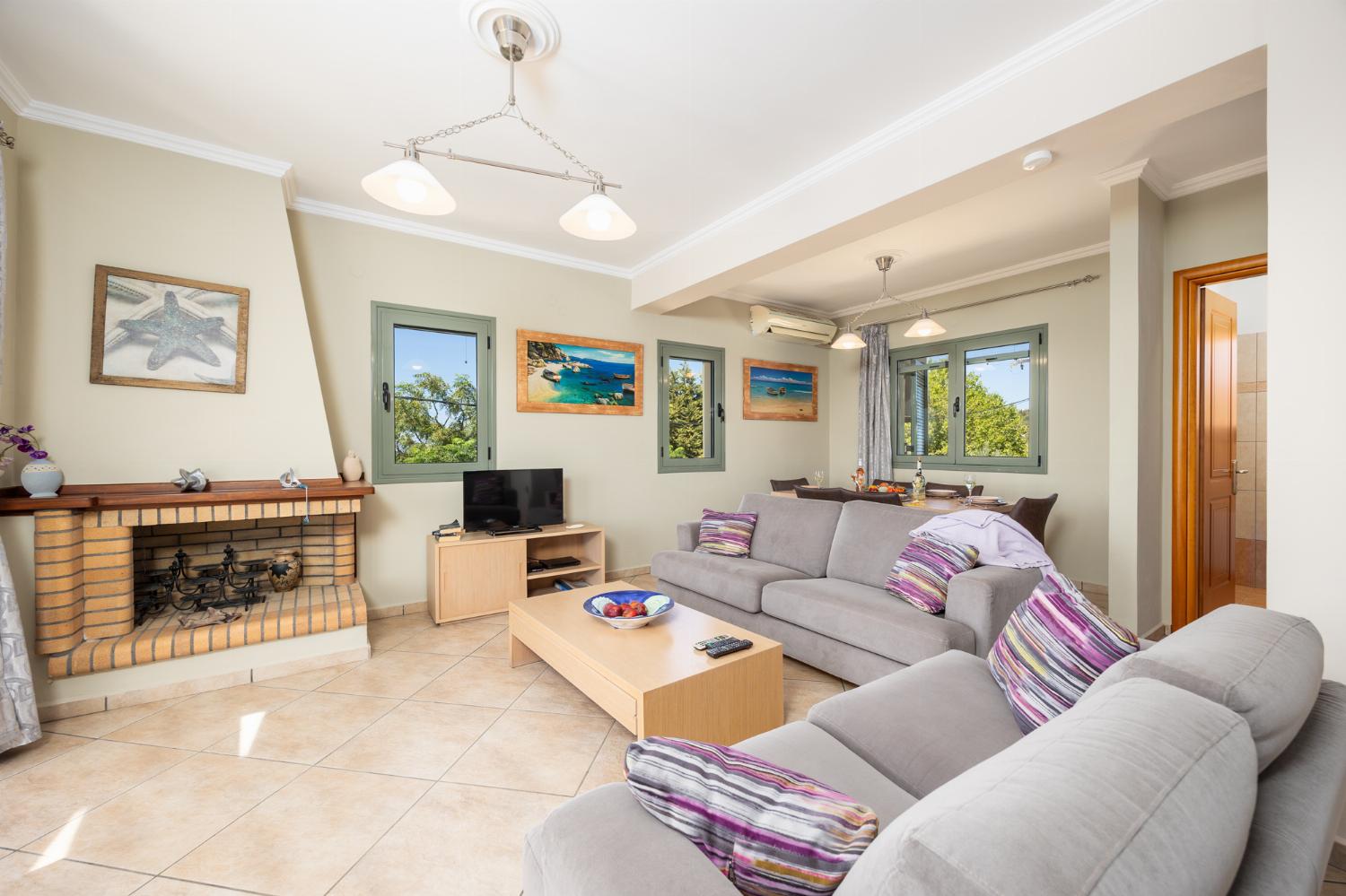 Open-plan living room with sofas, dining areas, kitchen, ornamental fireplace, A/C, WiFi internet, satellite TV, and sea views