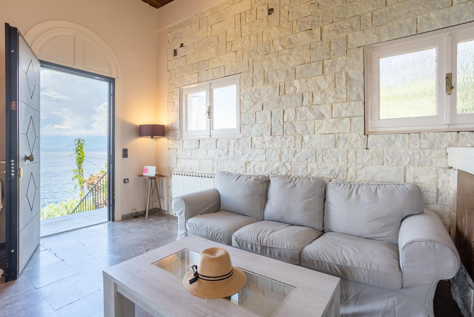 Open-plan living room with sofas, dining area, kitchen, ornamental fireplace, A/C, WiFi internet, satellite TV, and sea views