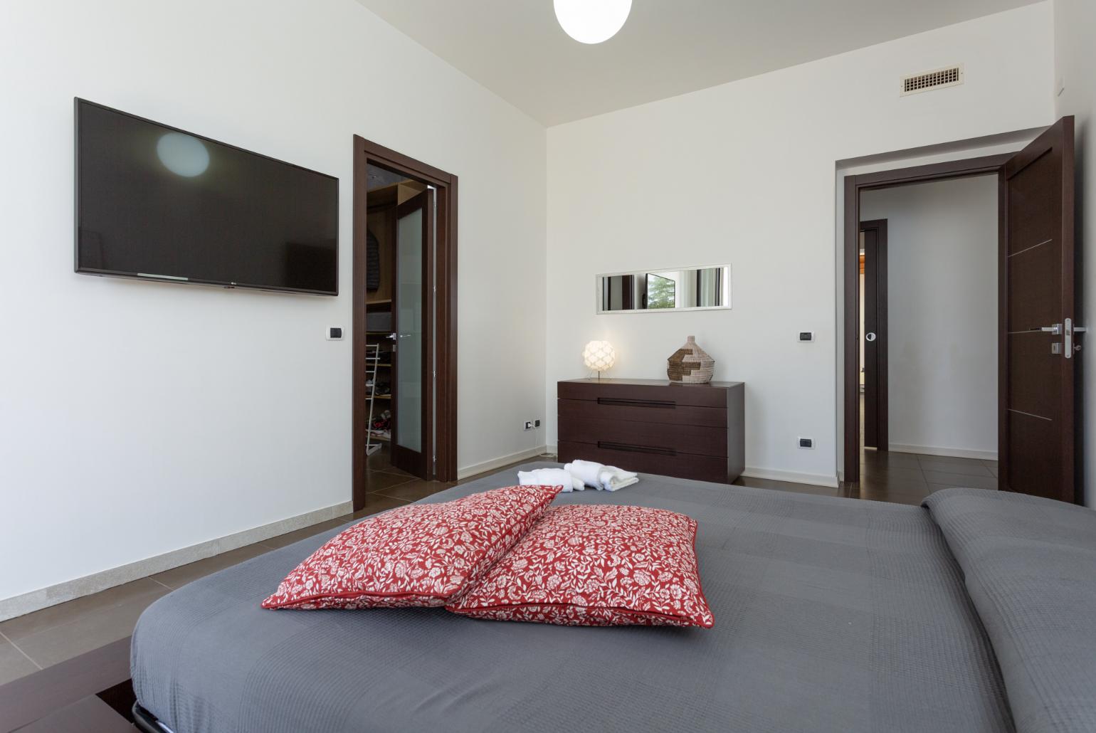 Double bedroom with en suite bathroom, A/C, TV, walk-in wardrobe, and terrace access