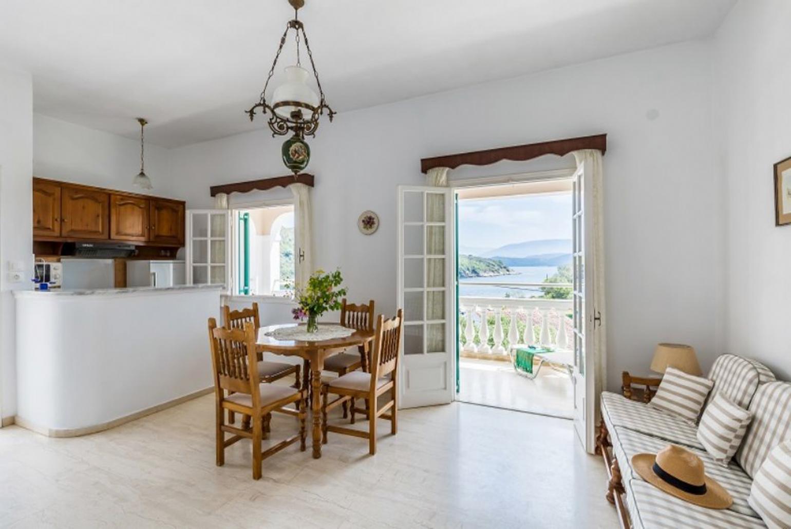 Open-plan living room with sofa, dining area, kitchen, WiFi internet, and terrace access with sea views