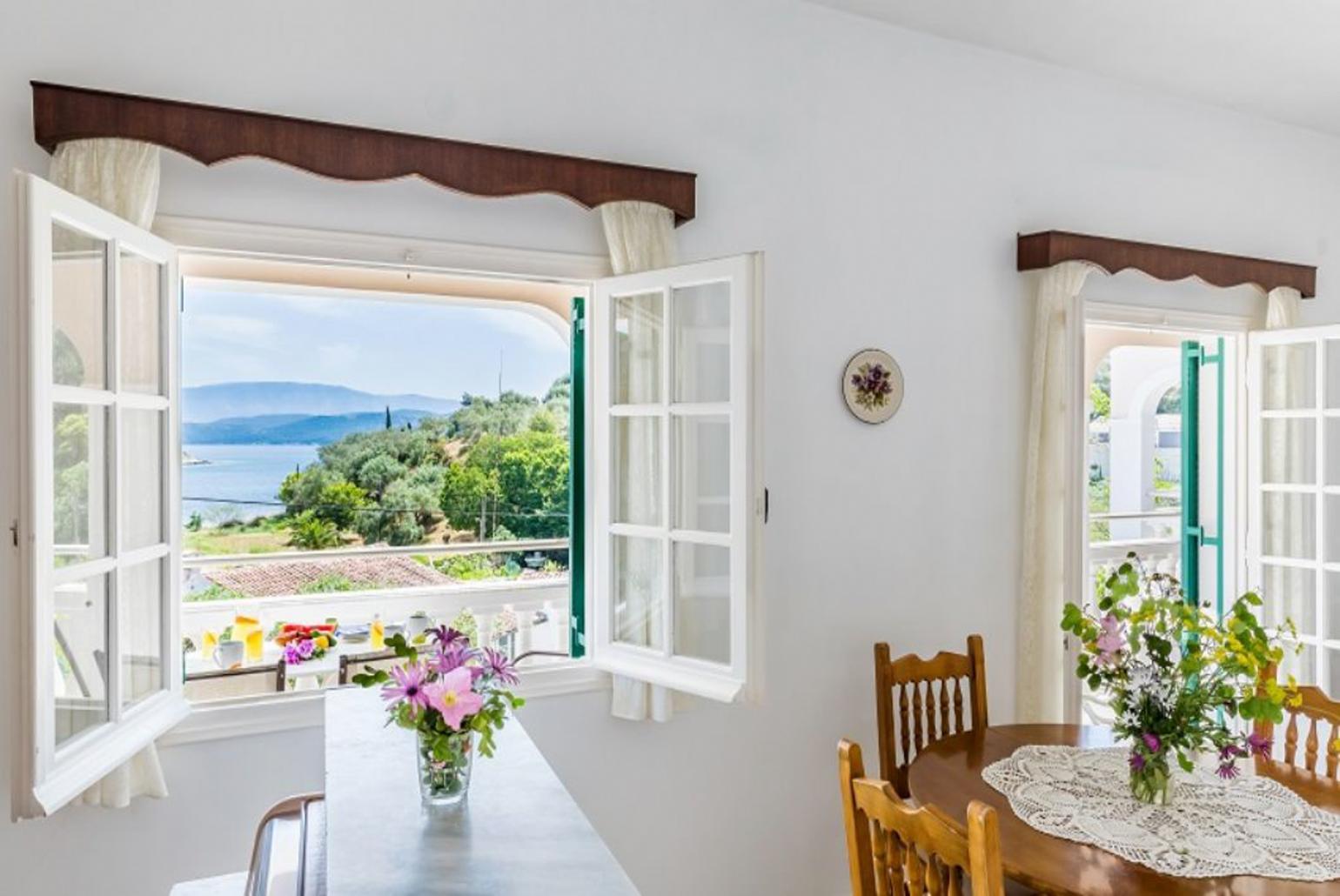 Open-plan living room with sofa, dining area, kitchen, WiFi internet, and terrace access with sea views