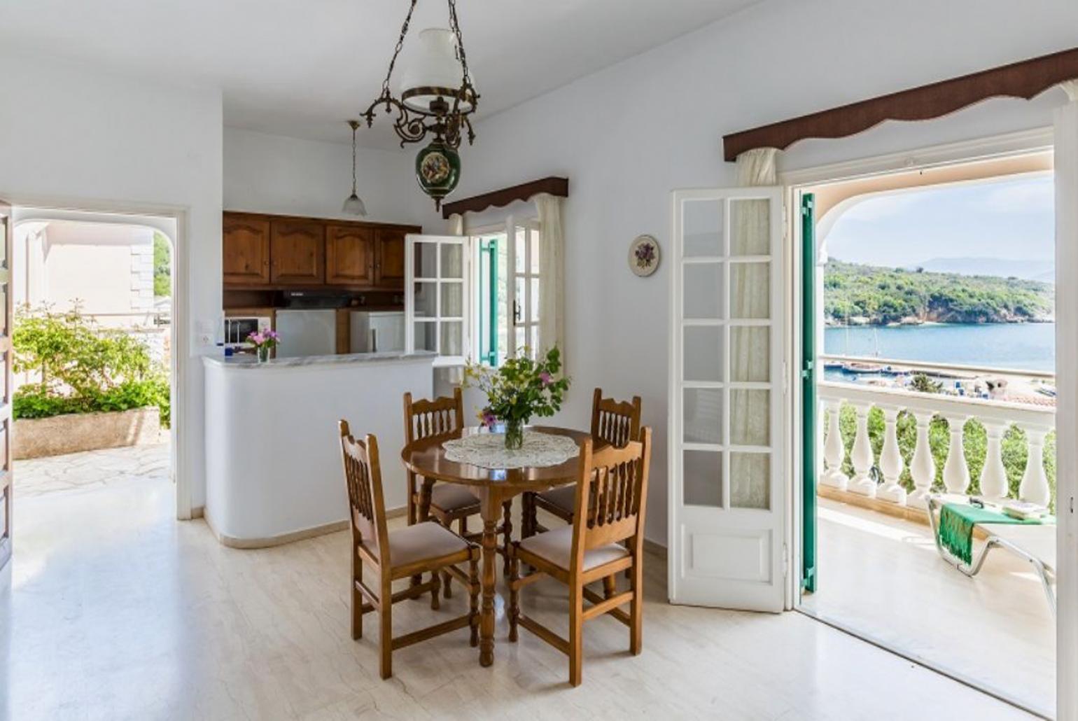 Open-plan living room with sofa, dining area, kitchen, WiFi internet, and terrace access with sea views