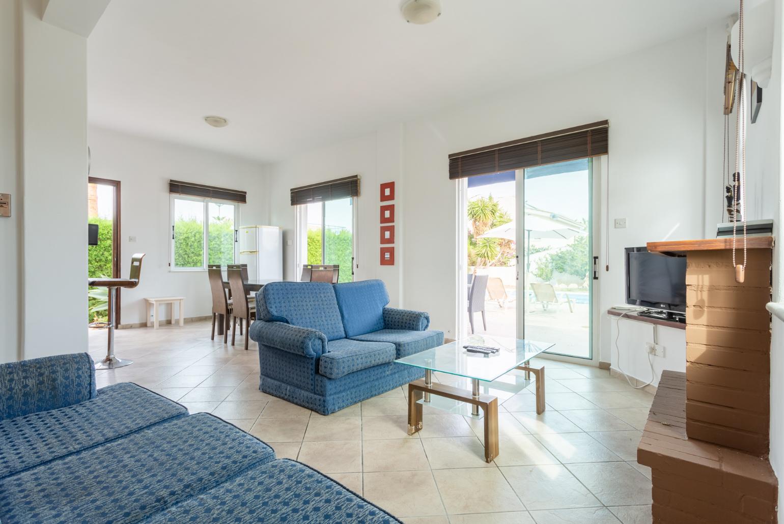 Open-plan living room with sofas, dining area, kitchen, ornamental fireplace, WiFi internet, satellite TV, and pool terrace access