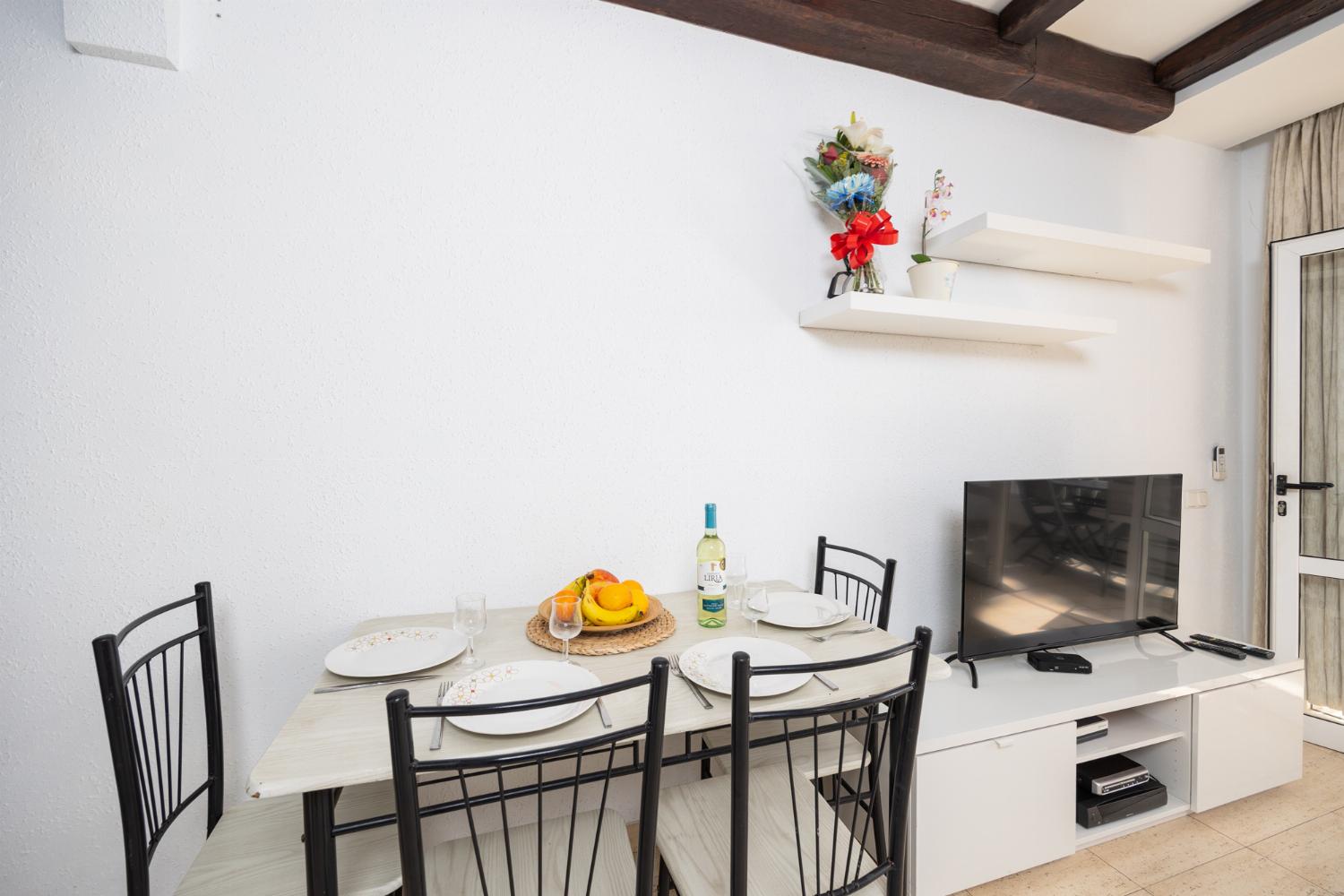 Open-plan living room with sofa, dining area, kitchen, A/C, WiFi internet, and satellite TV