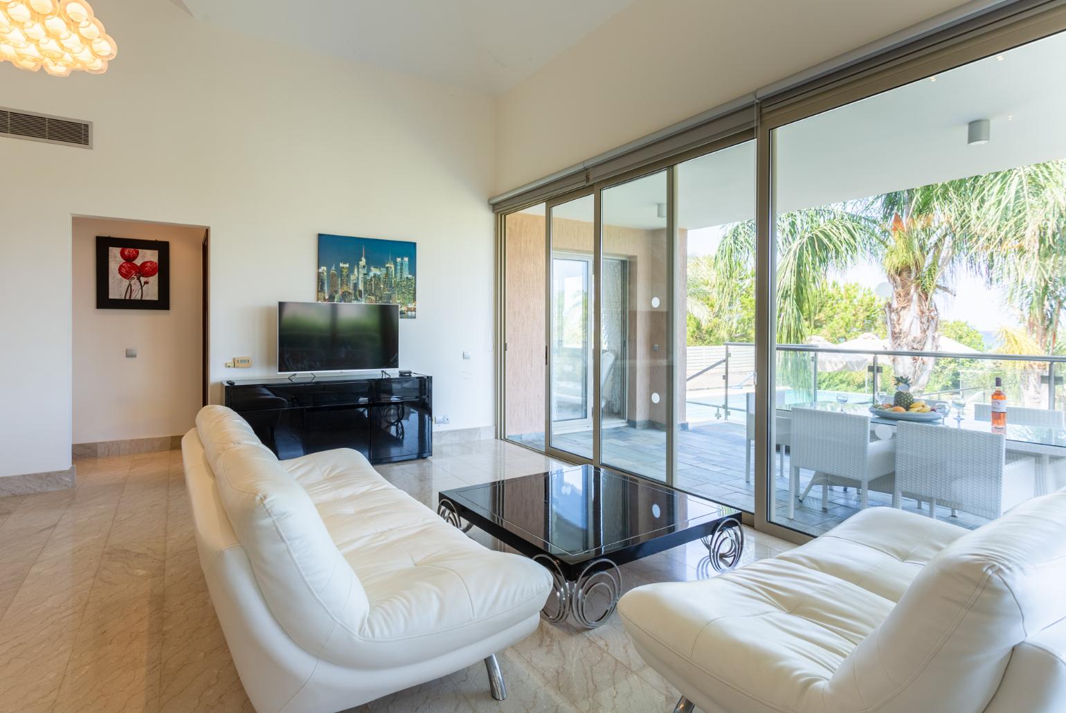 Open-plan living room with sofas, dining area, kitchen, ornamental fireplace, A/C, WiFi internet, satellite TV, and sea views