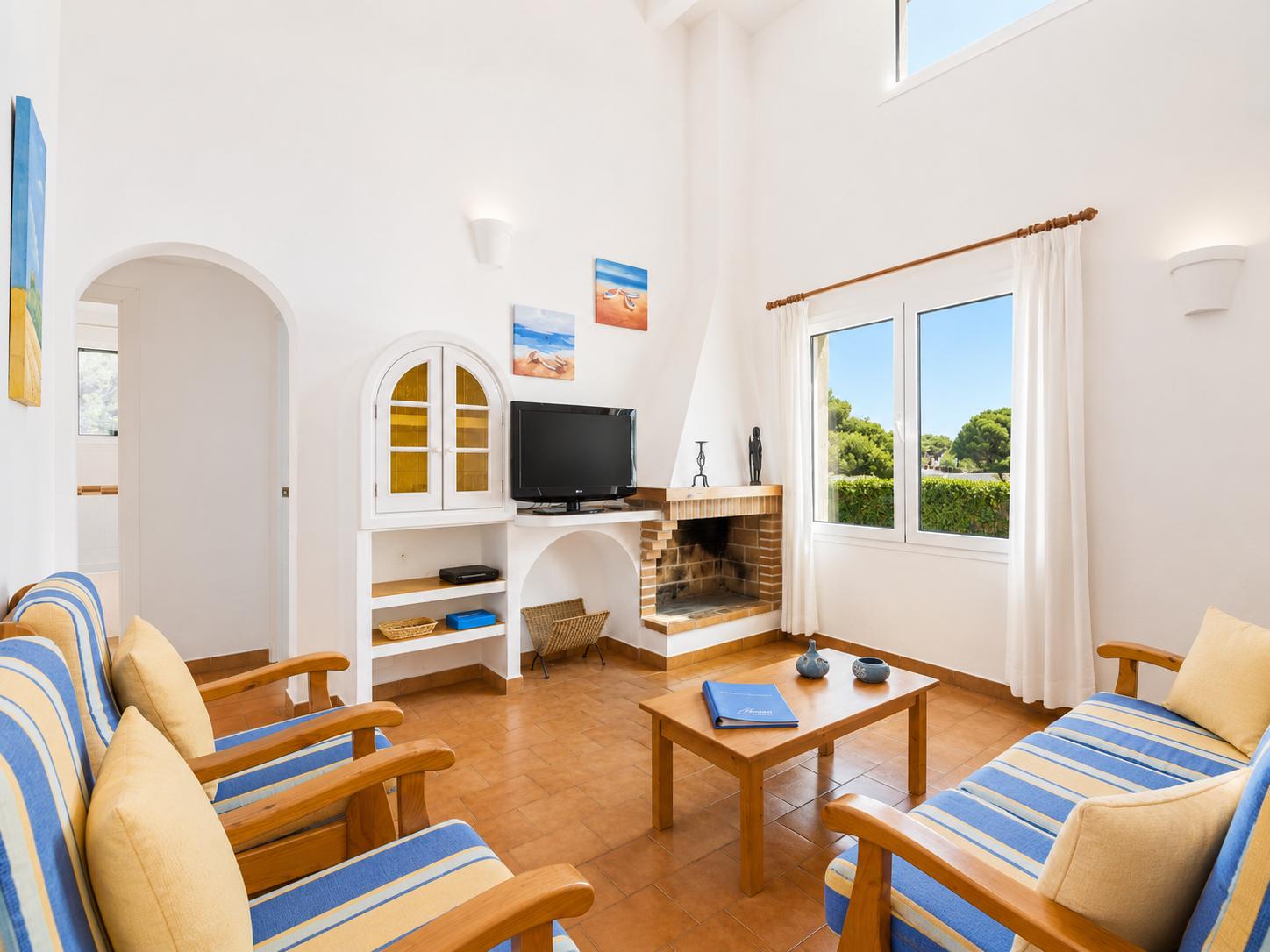 Open-plan living room with sofas, dining area, kitchen, ornamental fireplace, A/C, WiFi internet, and satellite TV