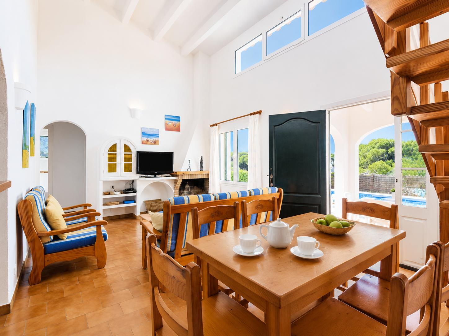 Open-plan living room with sofas, dining area, kitchen, ornamental fireplace, A/C, WiFi internet, and satellite TV
