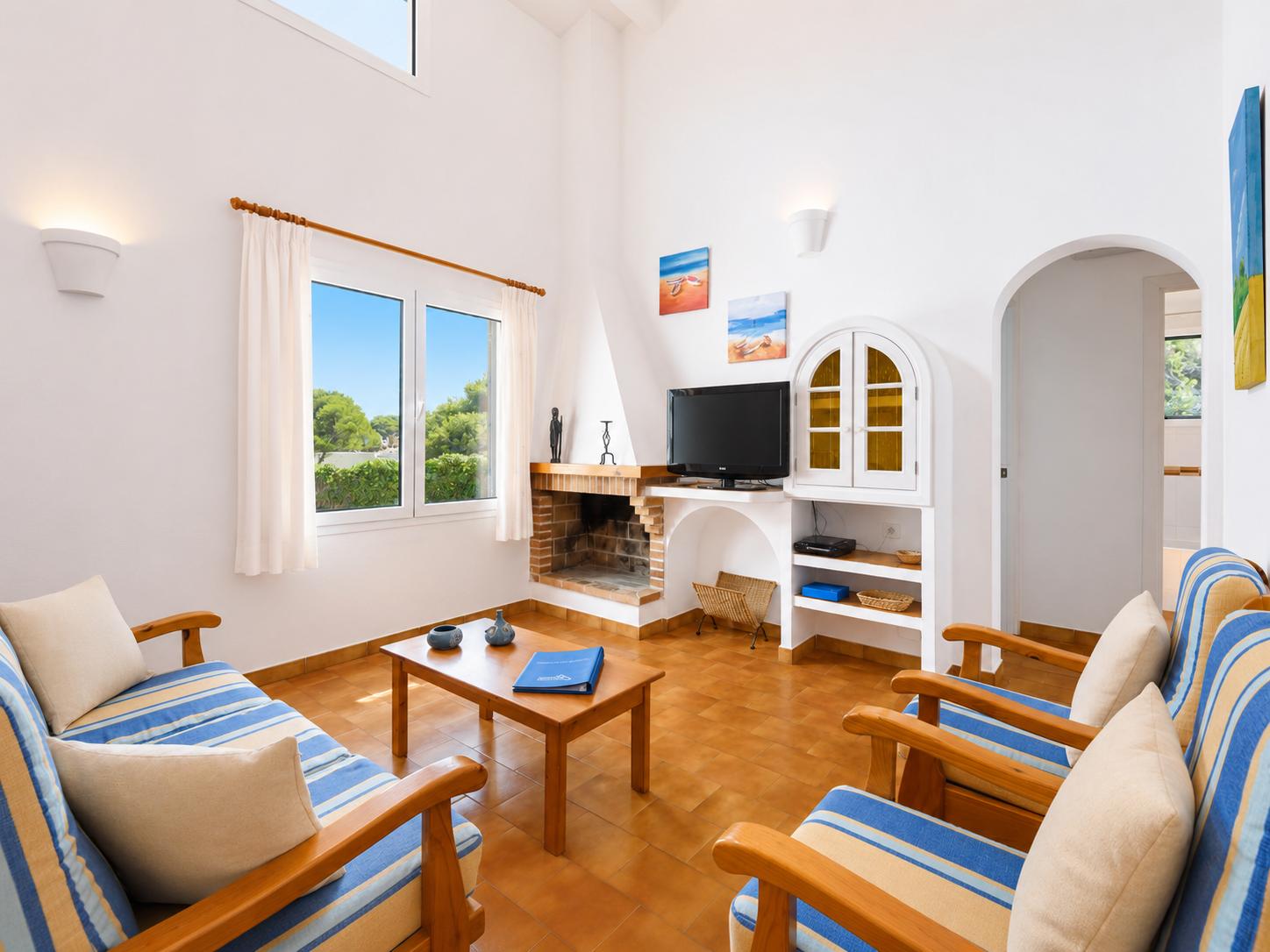 Open-plan living room with sofas, dining area, kitchen, ornamental fireplace, A/C, WiFi internet, and satellite TV