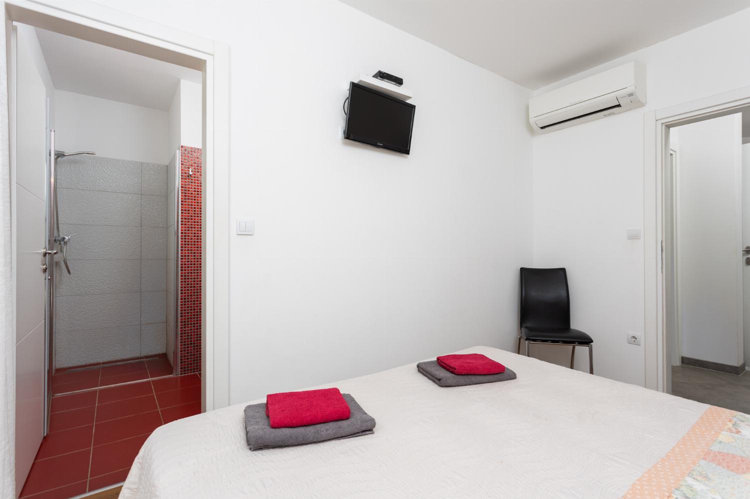 Double bedroom with en suite bathroom, A/C, and TV