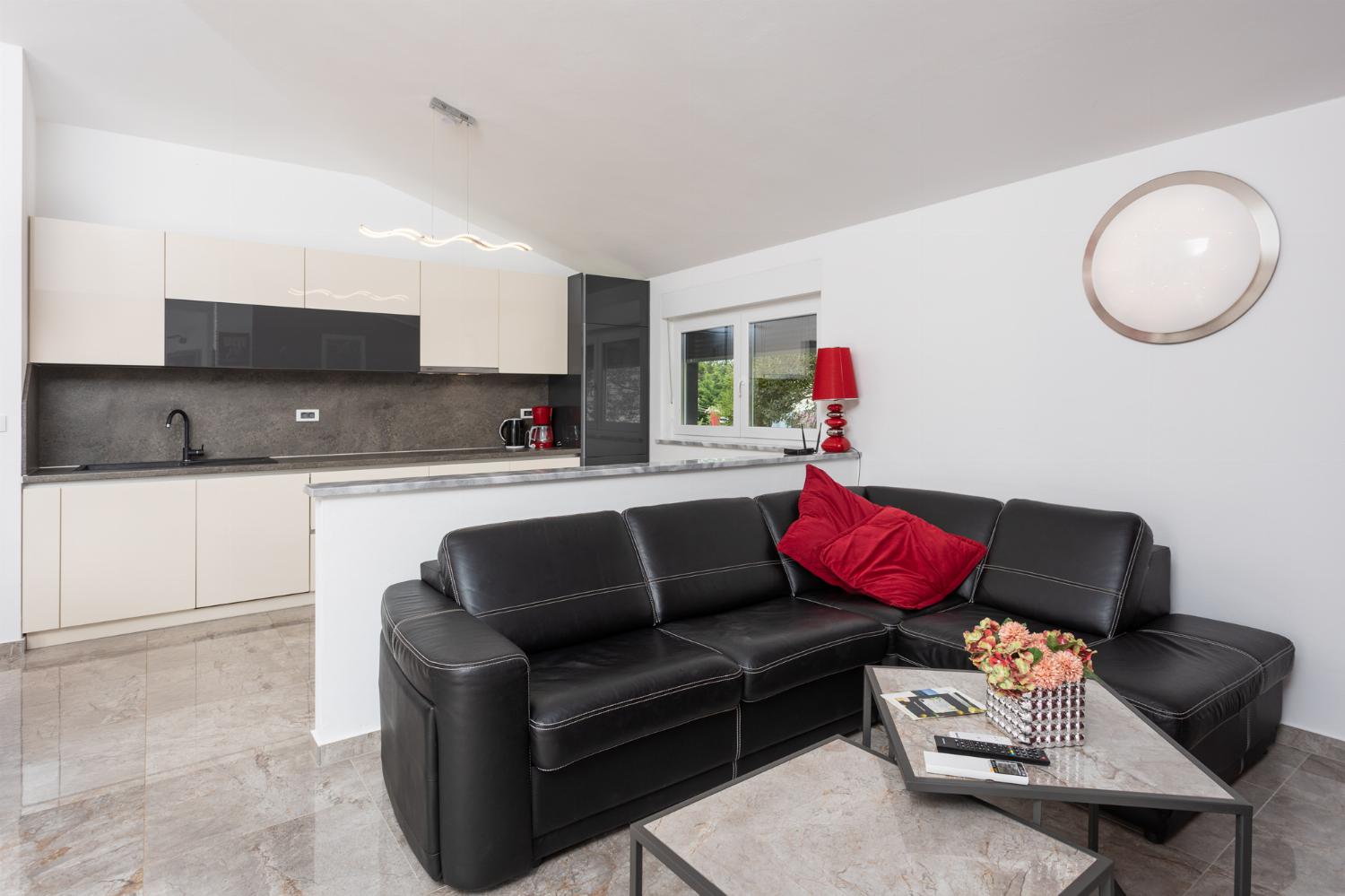 Open-plan living room with sofa, dining area, kitchen, A/C, WiFi internet, and satellite TV
