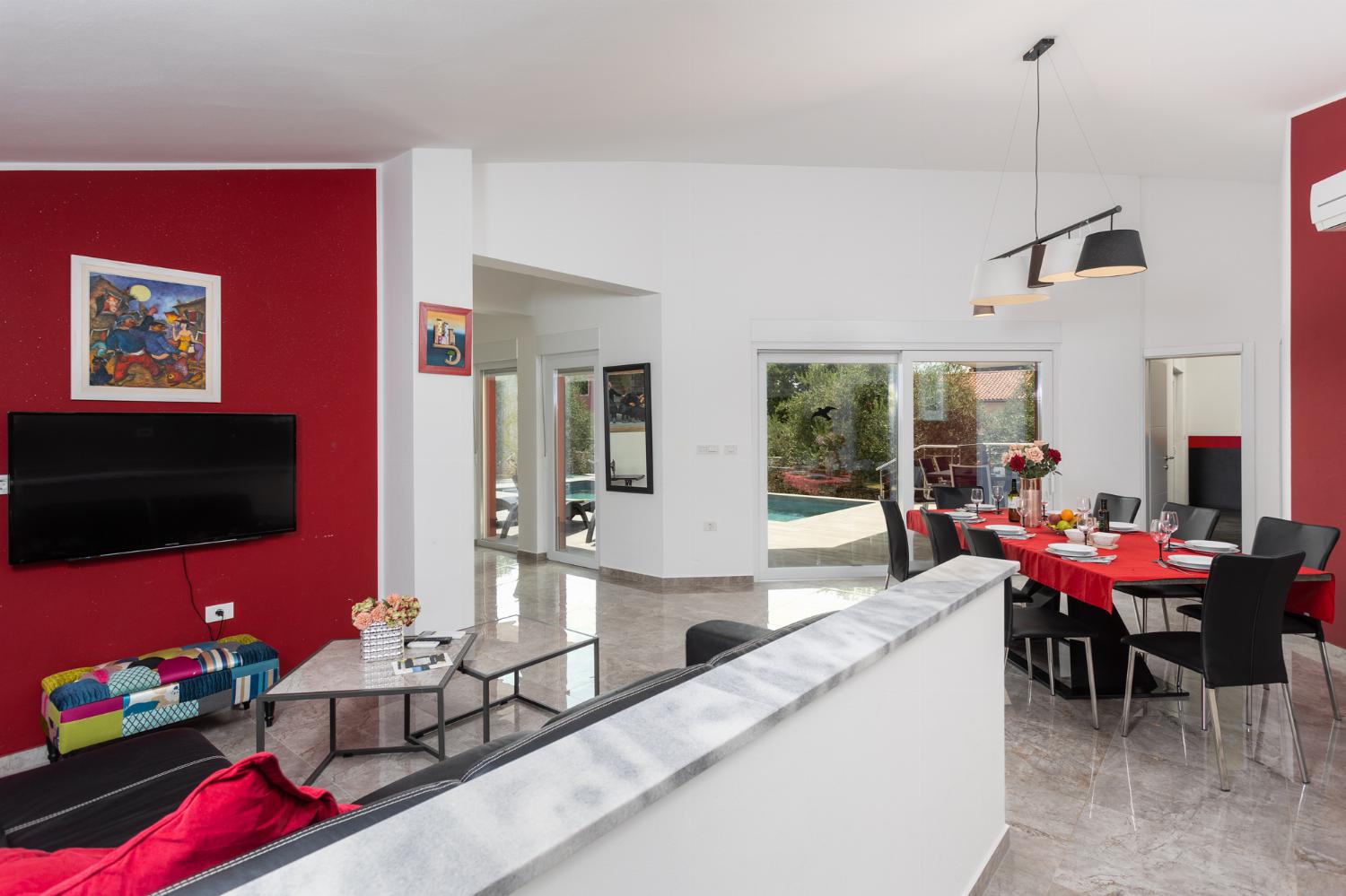 Open-plan living room with sofa, dining area, kitchen, A/C, WiFi internet, and satellite TV