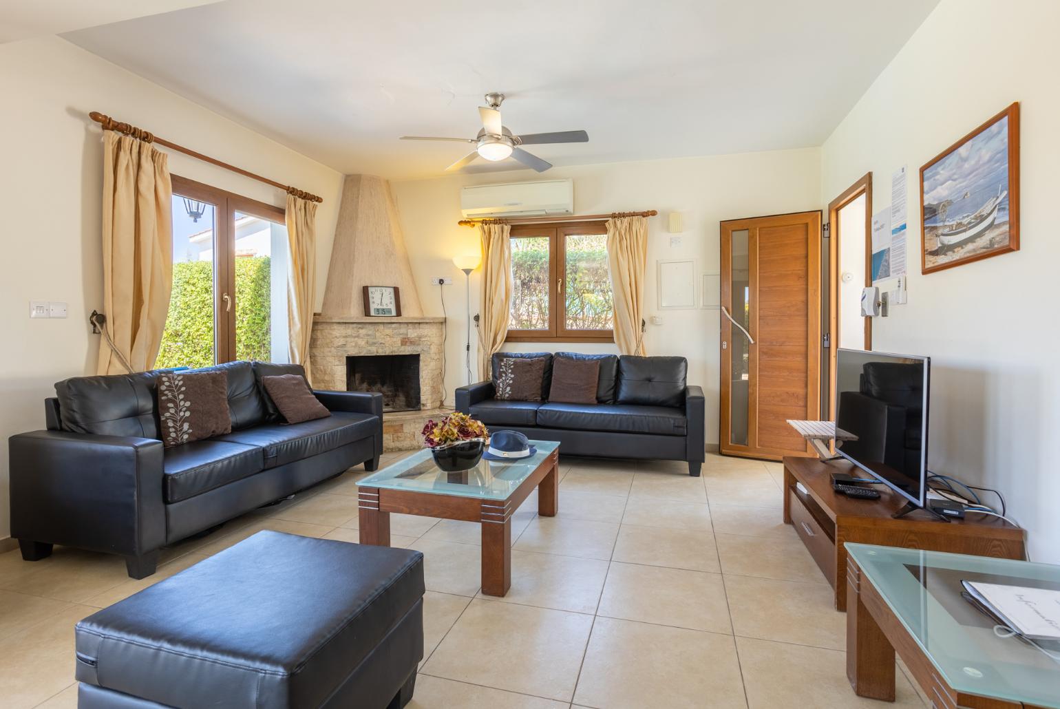 Open-plan living room with sofas, dining area, kitchen, ornamental fireplace, A/C, WiFi internet, and satellite TV