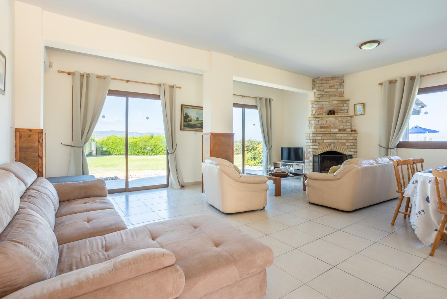 Open-plan living room with sofas, dining area, kitchen, ornamental fireplace, A/C, WiFi internet, satellite TV, and sea views