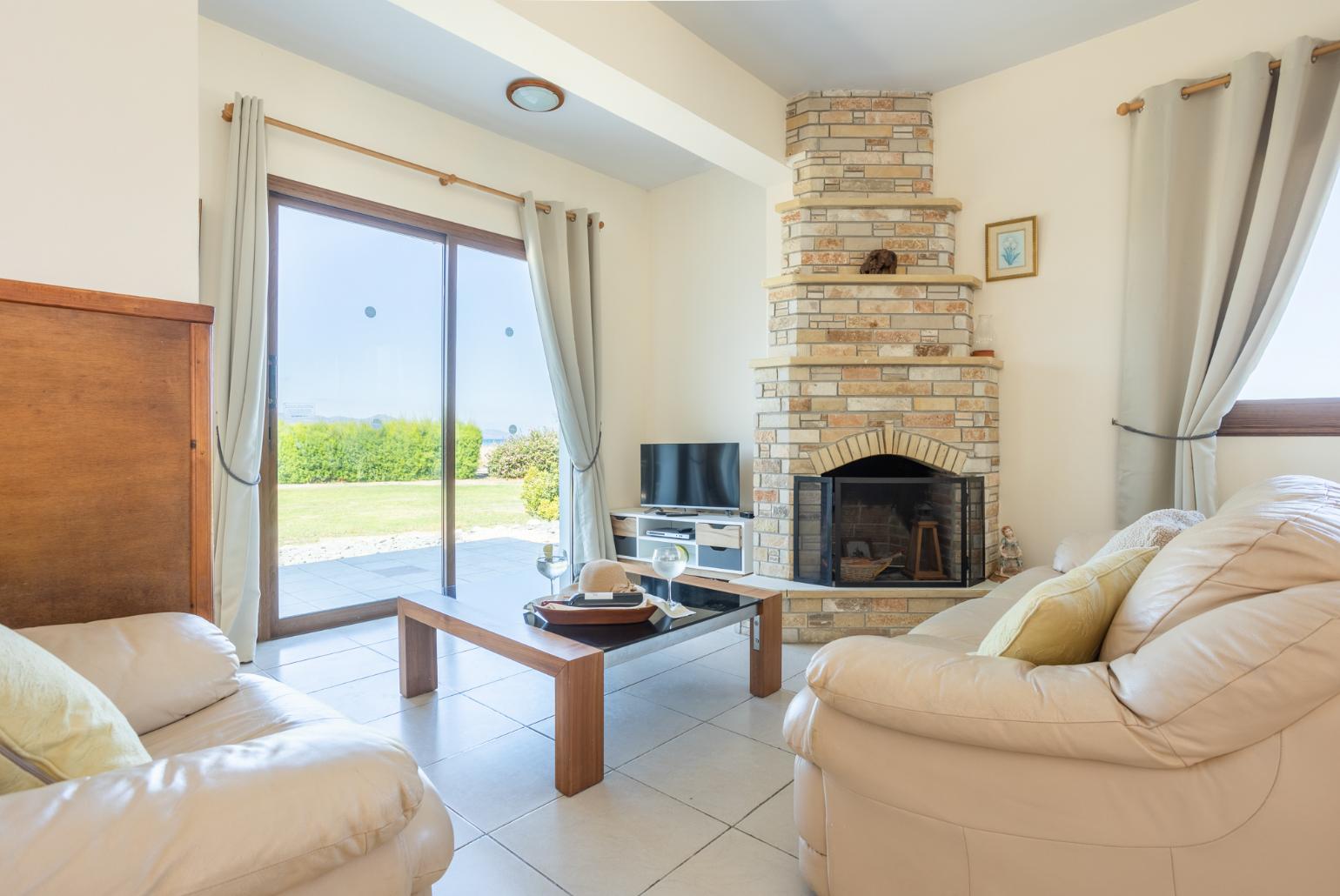 Open-plan living room with sofas, dining area, kitchen, ornamental fireplace, A/C, WiFi internet, satellite TV, and sea views