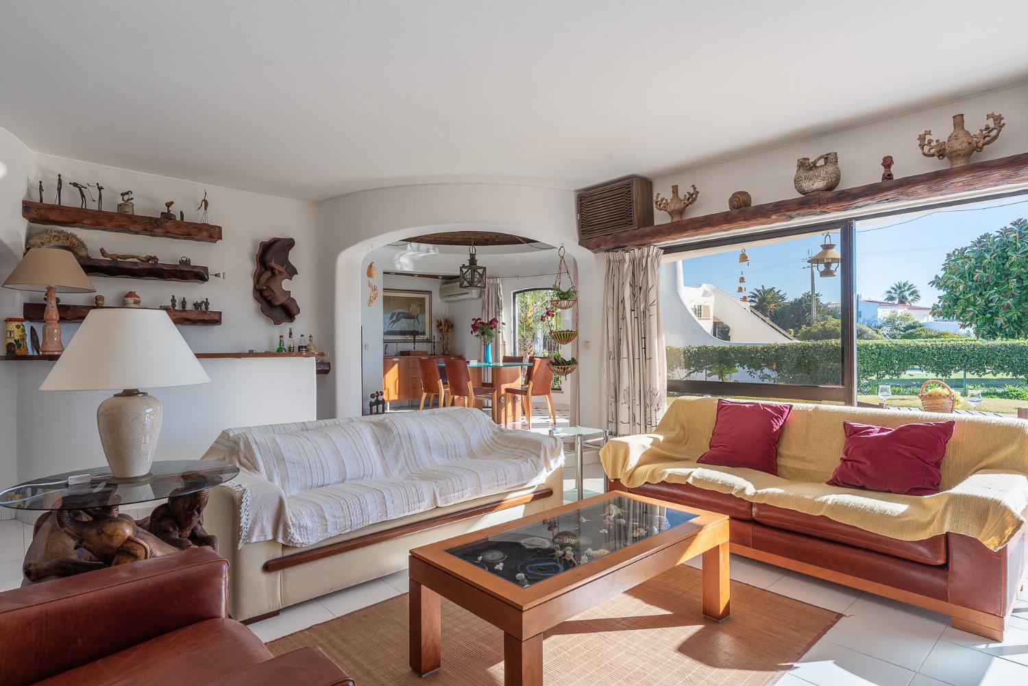 Open-plan living room with sofas, ornamental fireplace, dining area, kitchen, A/C, WiFi internet, satellite TV, DVD player, and pool terrace access