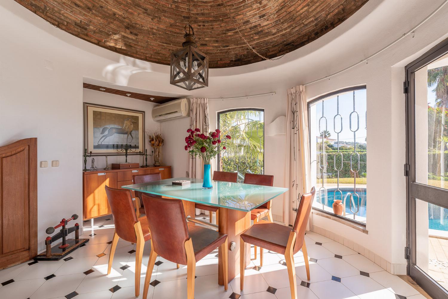 Open-plan living room with sofas, ornamental fireplace, dining area, kitchen, A/C, WiFi internet, satellite TV, DVD player, and pool terrace access