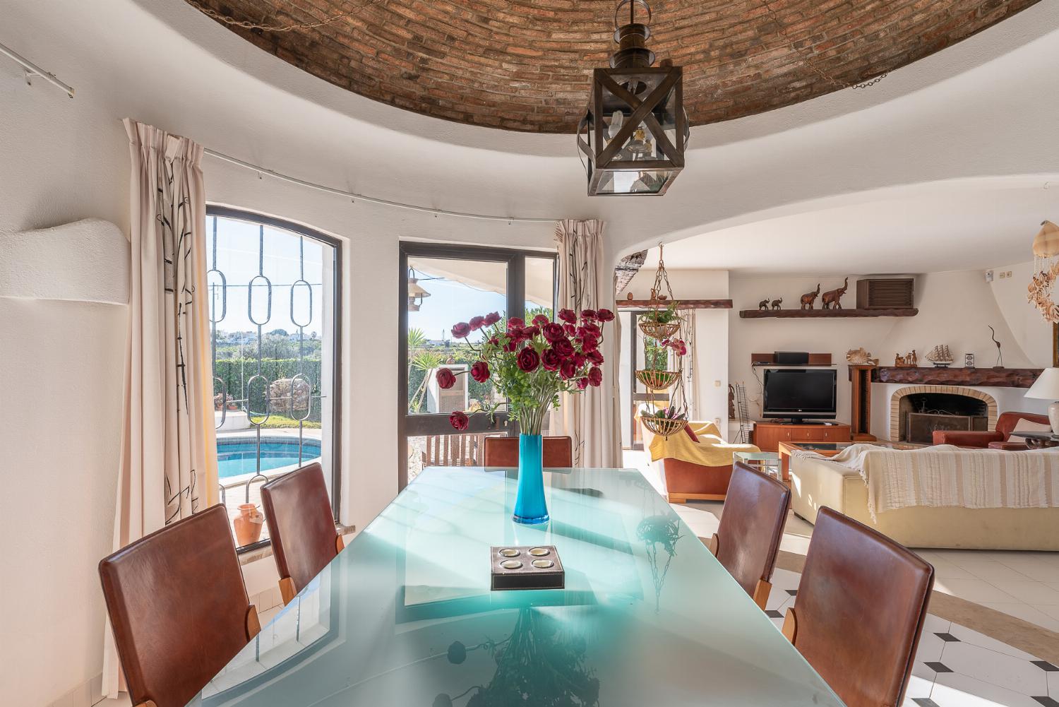 Open-plan living room with sofas, ornamental fireplace, dining area, kitchen, A/C, WiFi internet, satellite TV, DVD player, and pool terrace access