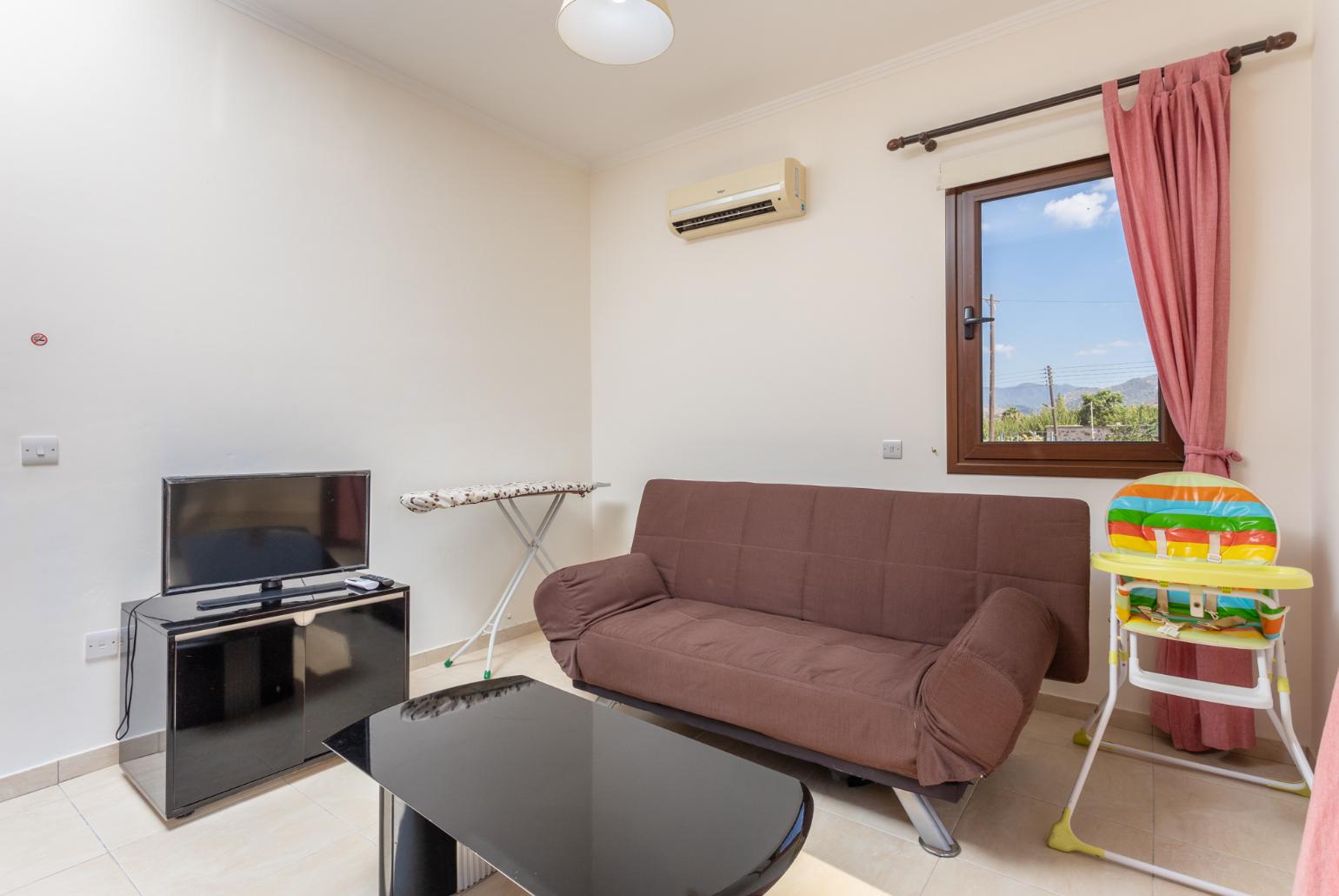 Living area on first floor with sofa, A/C, TV, and balcony access