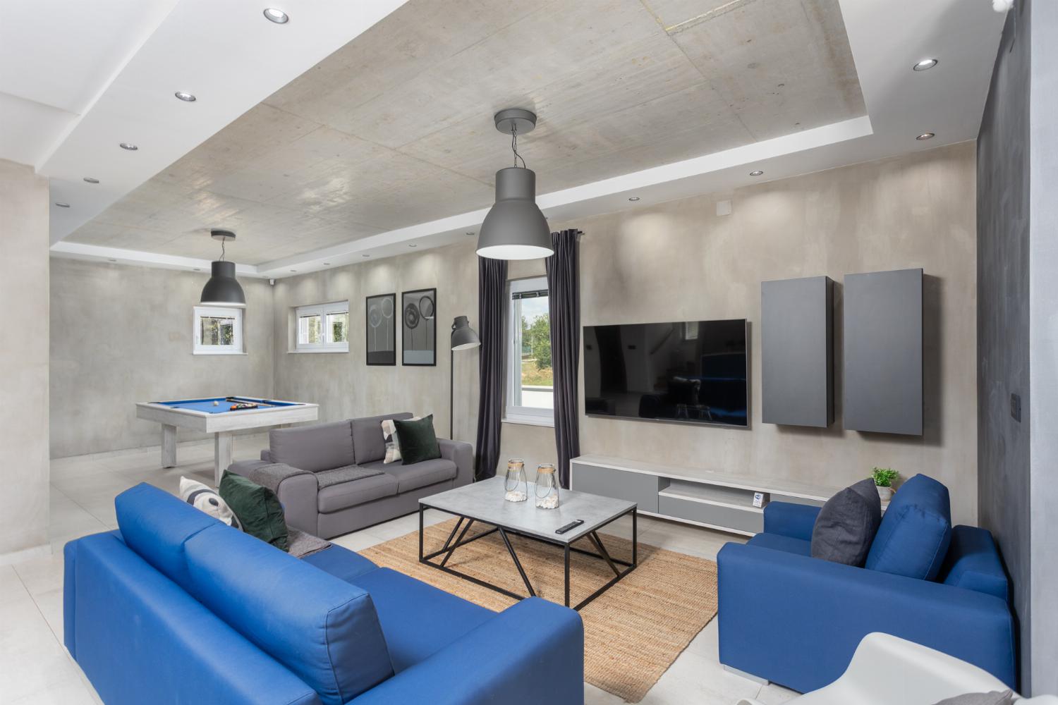Open-plan living room with sofas, dining area, kitchen, pool table, ornamental fireplace, A/C, WiFi internet, and satellite TVs