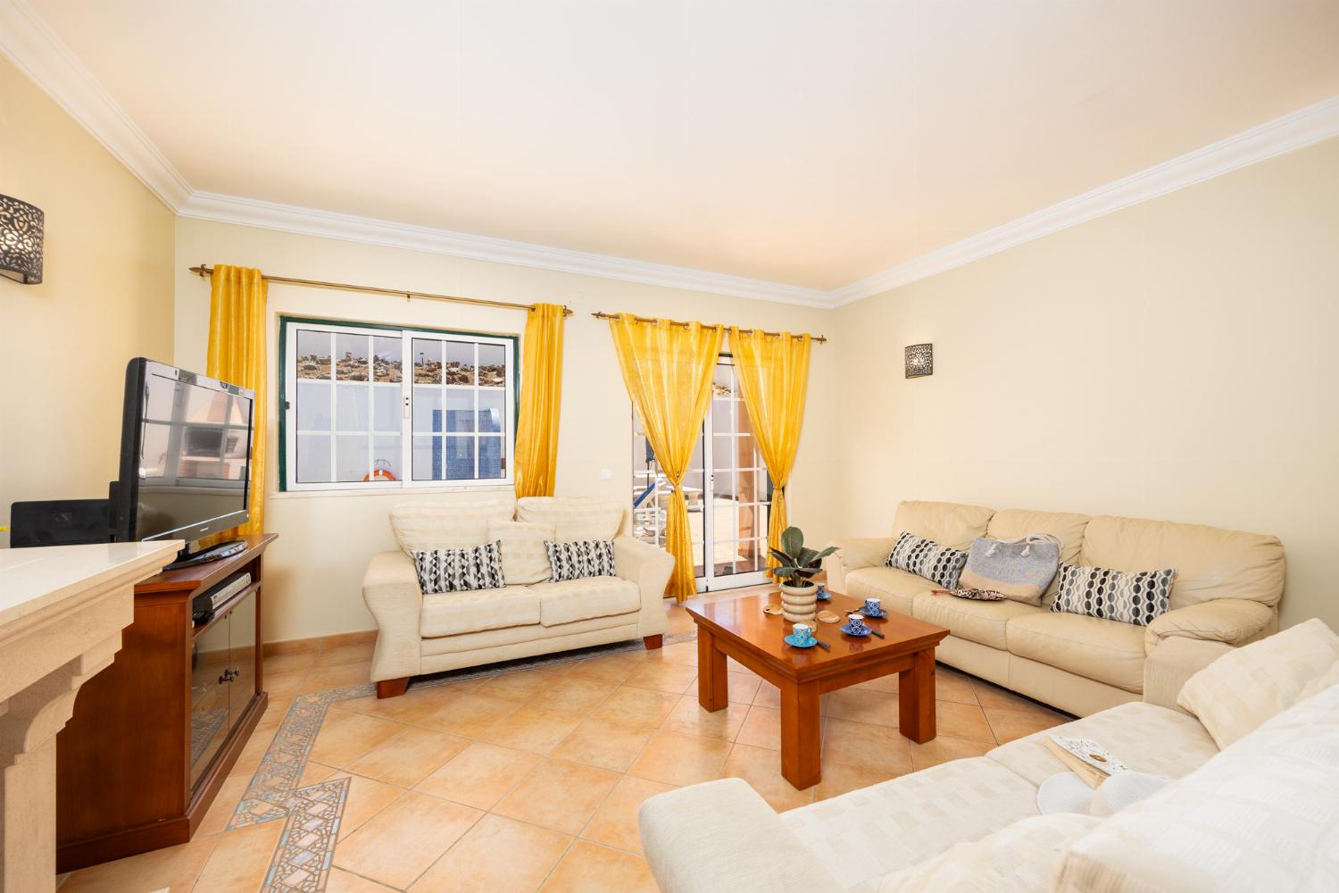 Open-plan living room with sofas, dining area, ornamental fireplace, A/C, WiFi internet, and satellite TV