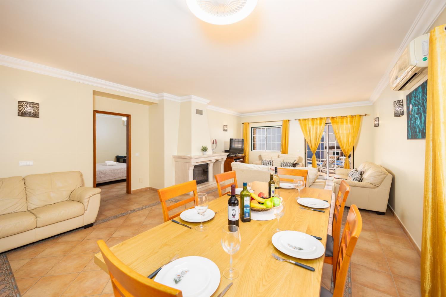 Open-plan living room with sofas, dining area, ornamental fireplace, A/C, WiFi internet, and satellite TV